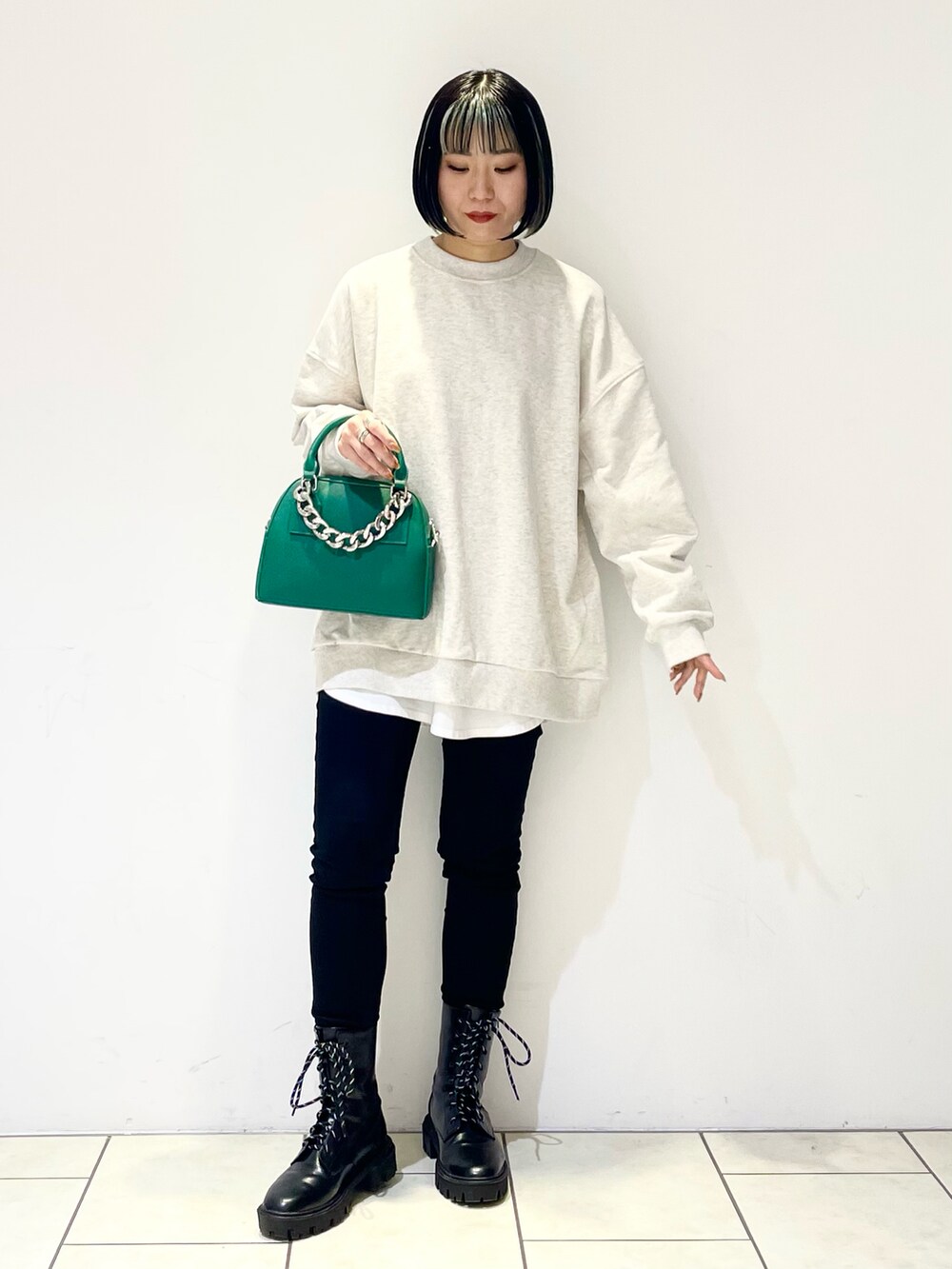 ベージュ系のスウェット、ホワイト系のTシャツ/カットソー、グリーン系のショルダーバッグを着用したレディースの冬コーディネートの2枚目の写真