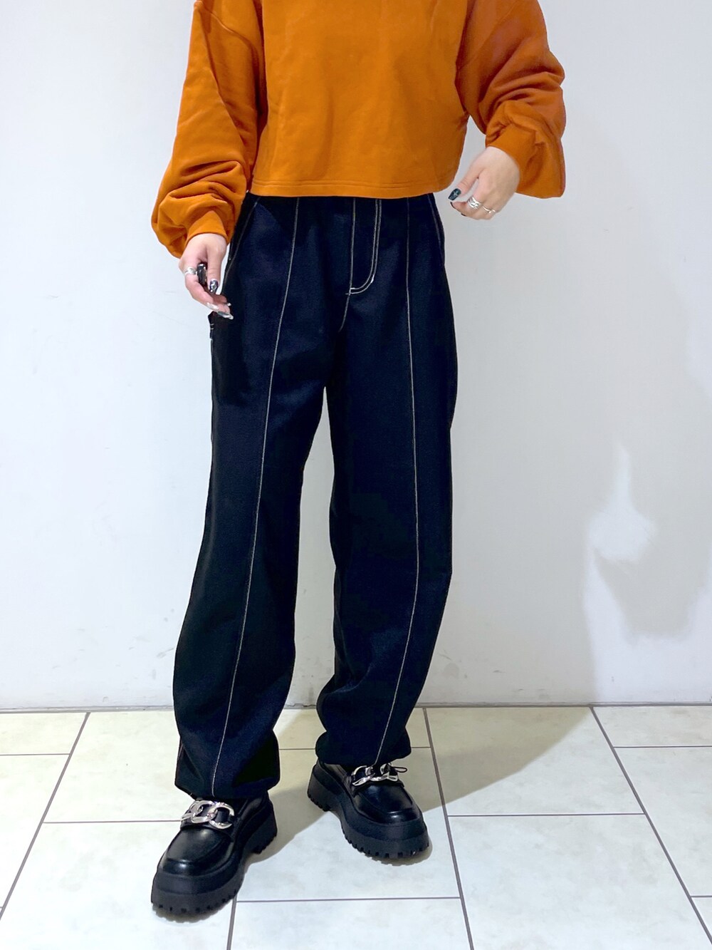 オレンジ系のスウェット、ブラック系のその他パンツ、ブラック系のローファーを着用したレディースの秋コーディネートの4枚目の写真