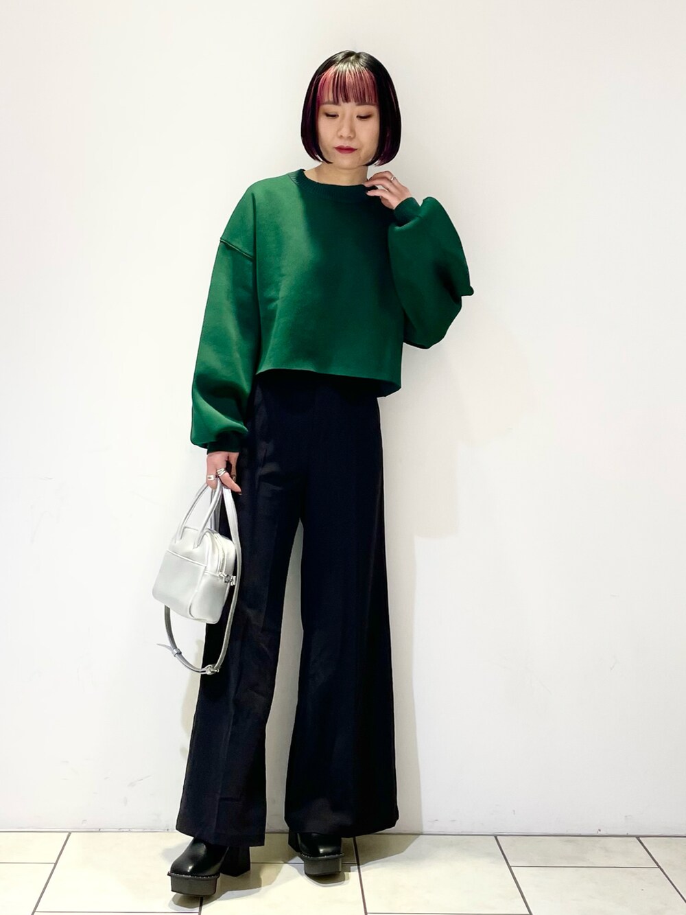 グリーン系のニット/セーター、シルバー系のボストンバッグ、ブラック系のスラックスを着用したレディースの春コーディネートの2枚目の写真
