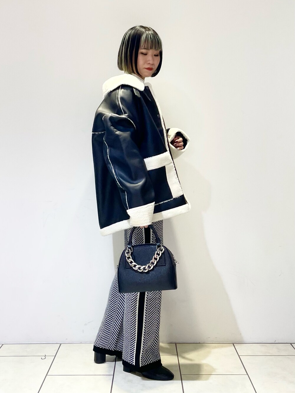 ブラック系のブルゾン、ホワイト系のニット/セーター、ブラック系のショルダーバッグを着用したレディースの冬コーディネートの2枚目の写真