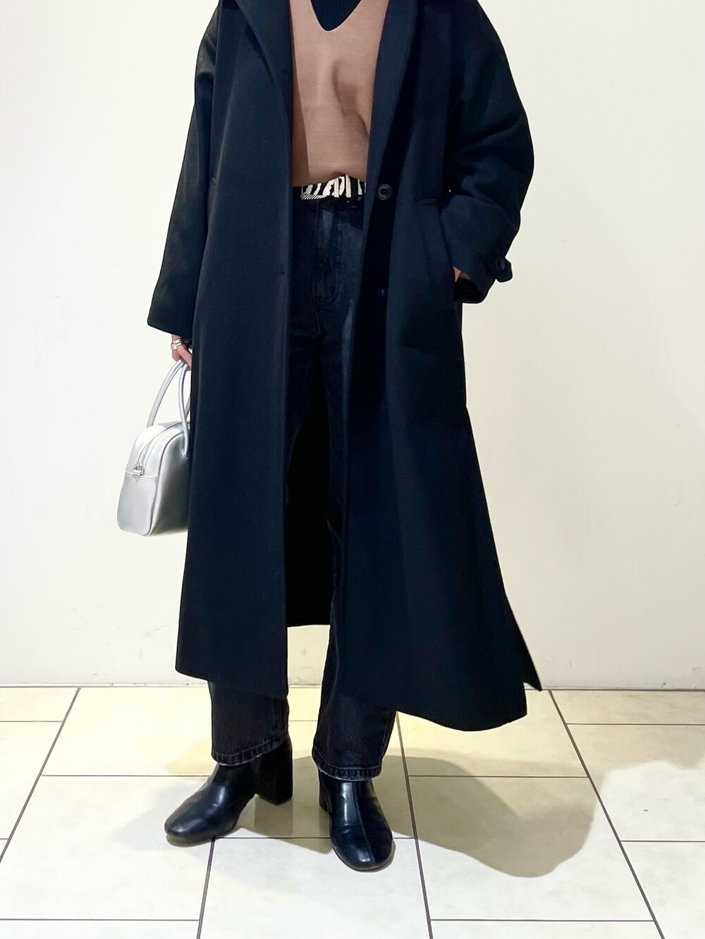 ブラック系のチェスターコート、ブラウン系のニット/セーター、ブラック系のニット/セーターを着用したレディースの春コーディネートの5枚目の写真