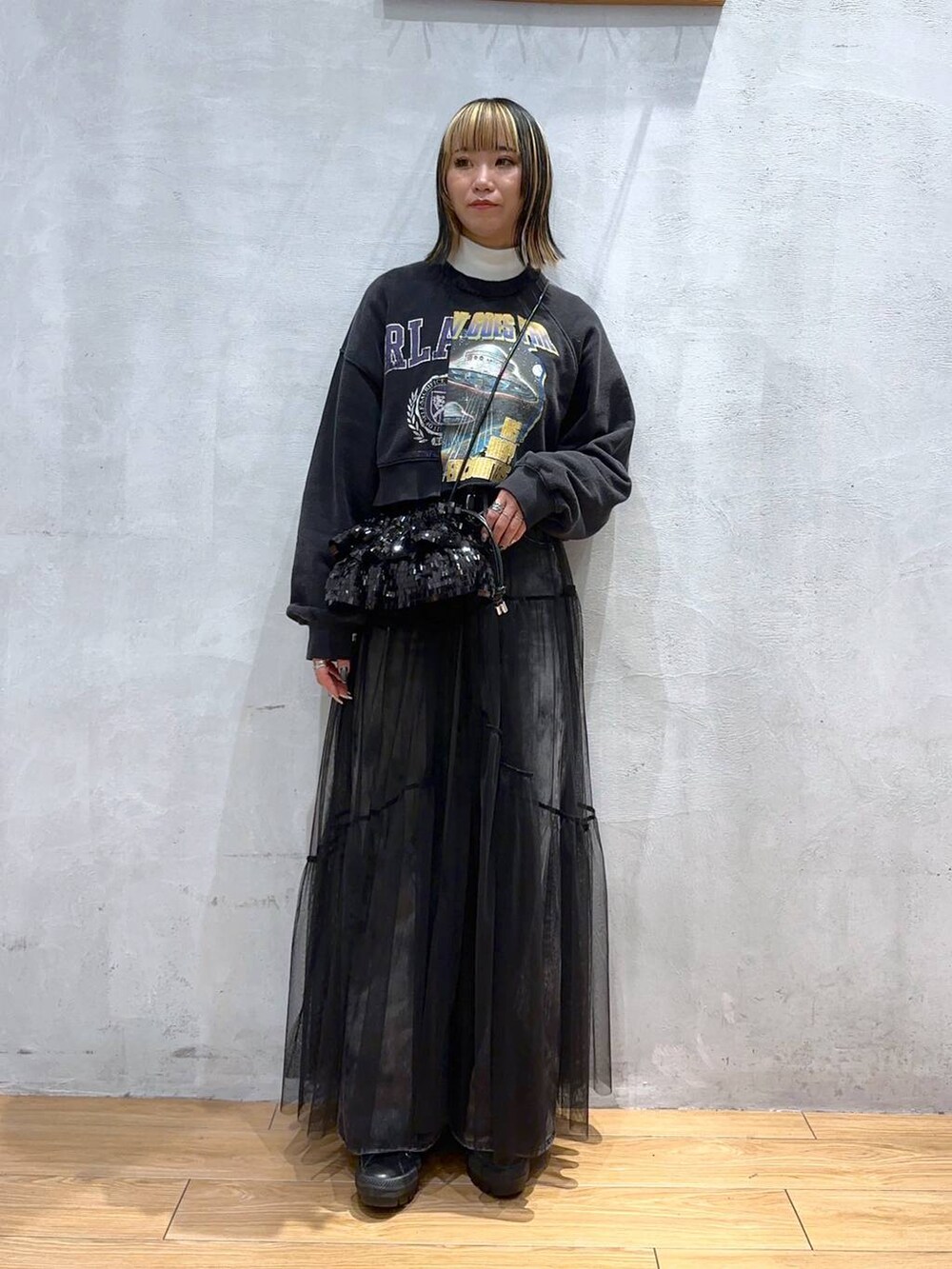 ブラック系のスウェット、ブラック系のデニムパンツ、ブラック系のワンピースを着用したレディースの冬コーディネートの2枚目の写真