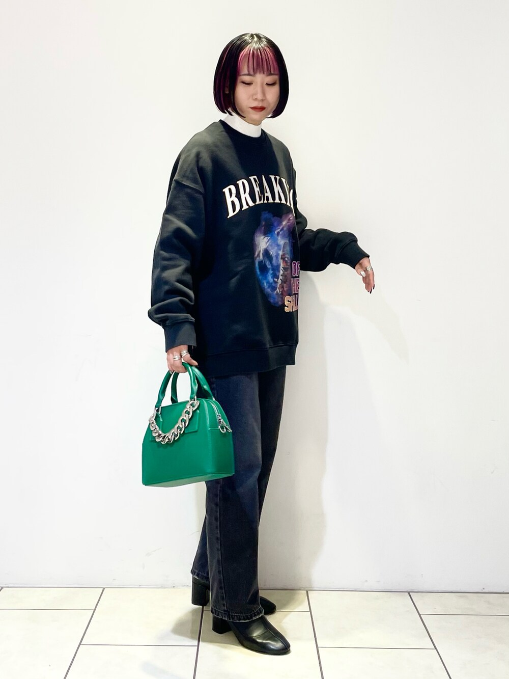 ブラック系のトップス、ホワイト系のニット/セーター、グリーン系のショルダーバッグを着用したレディースの冬コーディネートの3枚目の写真