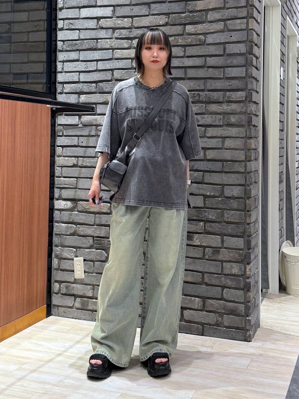 ブルー系のデニムパンツ、ブラック系のサンダル、ブラック系のTシャツ/カットソーを着用したレディースの春コーディネートの2枚目の写真