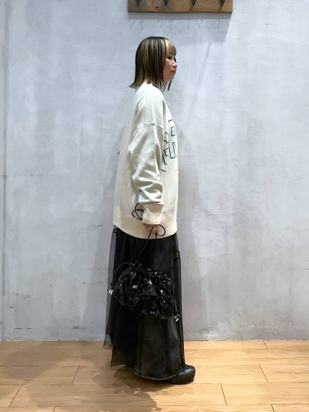 ベージュ系のニット/セーター、ブラック系のデニムパンツ、ブラック系のワンピースを着用したレディースの冬コーディネートの4枚目の写真