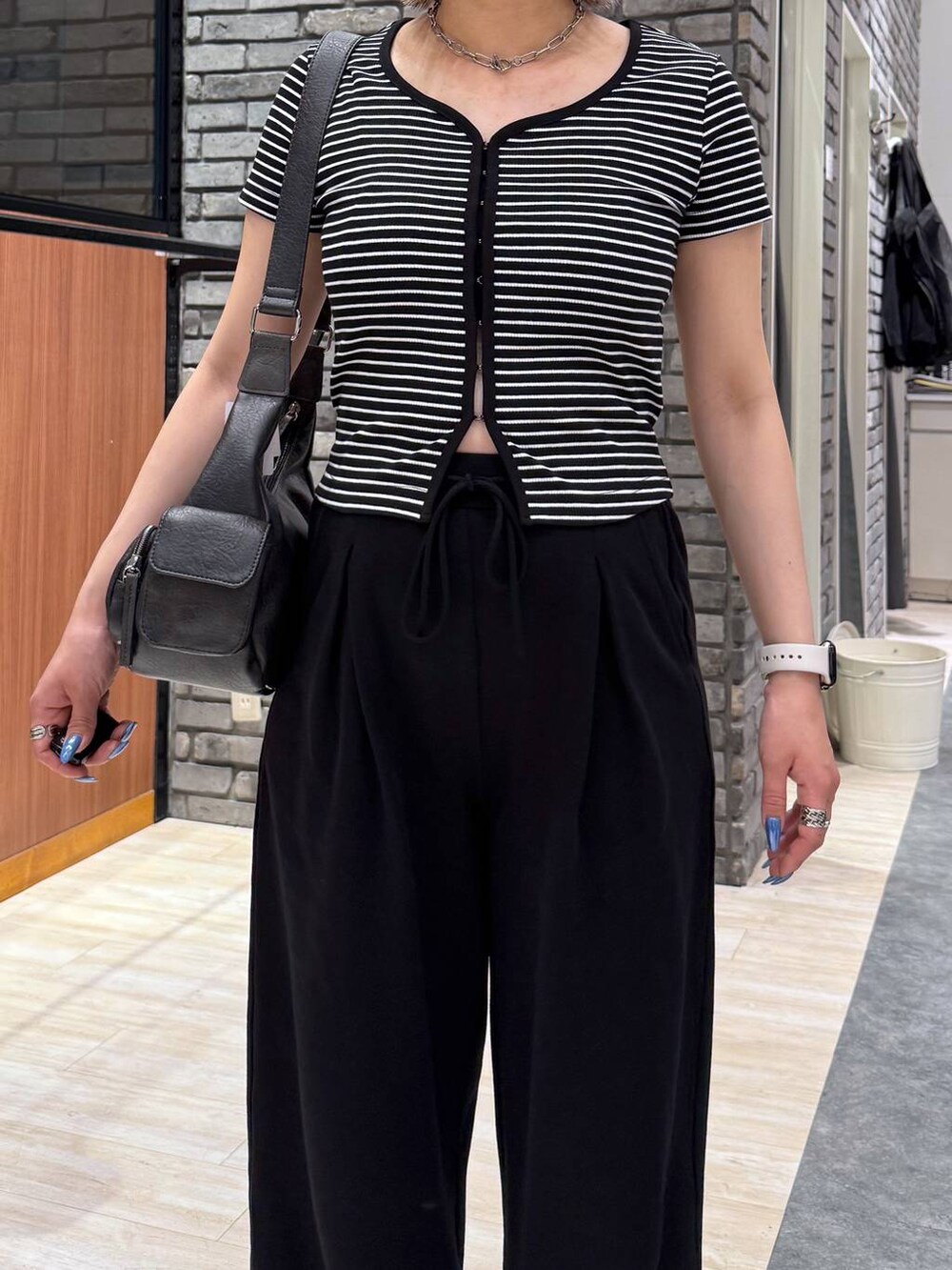 ブラック系のショルダーバッグ、ブラック系のTシャツ/カットソー、ブラック系のスウェットパンツを着用したレディースの春コーディネートの2枚目の写真