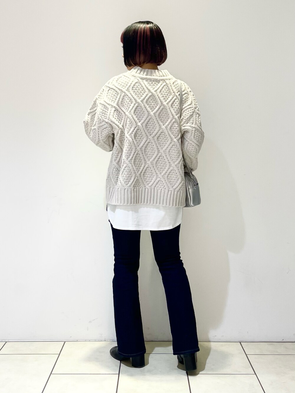 ベージュ系のニット/セーター、ホワイト系のTシャツ/カットソー、シルバー系のボストンバッグを着用したレディースの春コーディネートの2枚目の写真