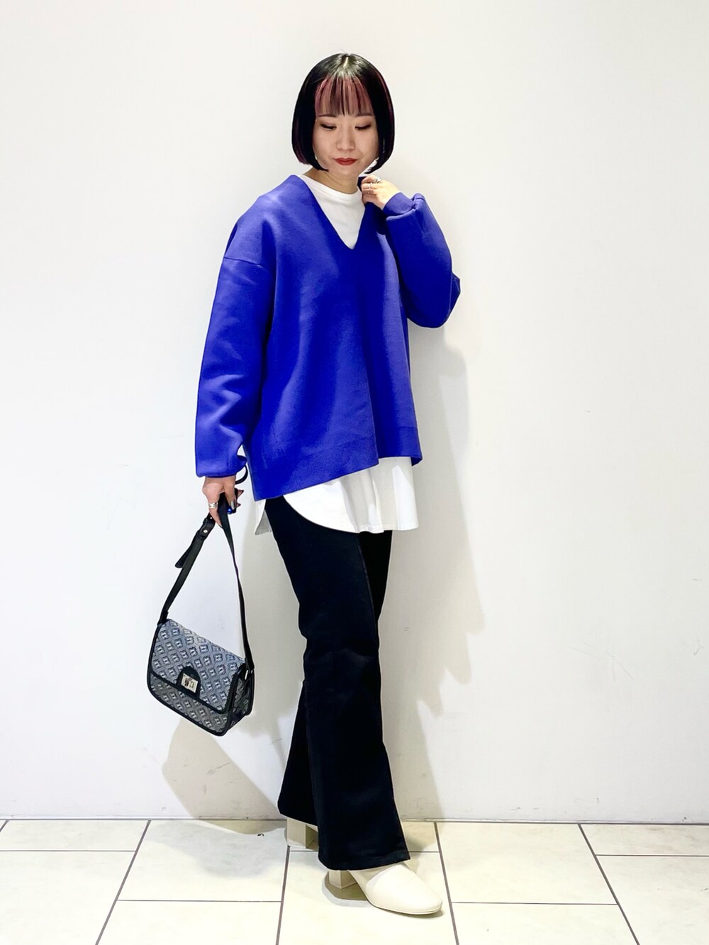 ブルー系のニット/セーター、ホワイト系のTシャツ/カットソー、ブラック系のショルダーバッグを着用したレディースの冬コーディネートの2枚目の写真