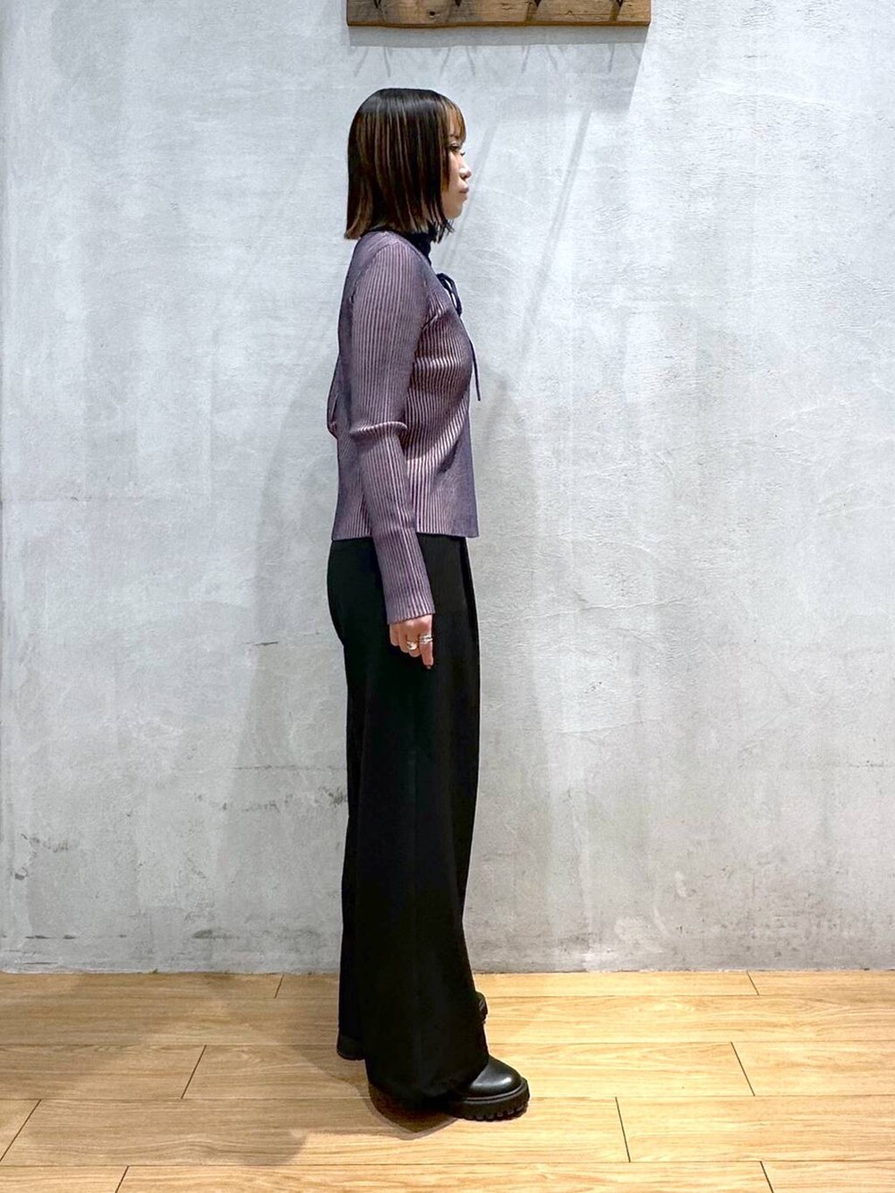 ブラック系のスラックス、ブルー系のニット/セーター、ブラック系のベルトを着用したレディースの冬コーディネートの2枚目の写真