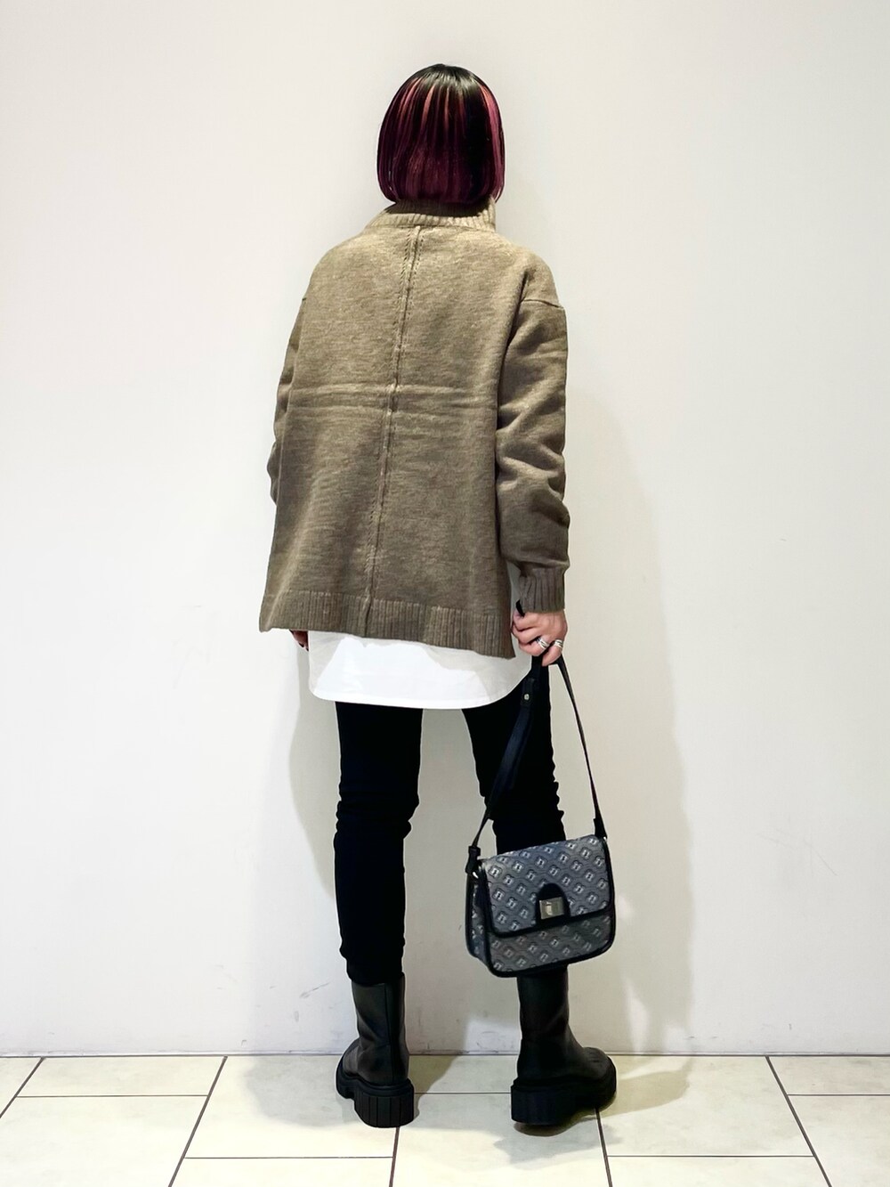 ブラウン系のニット/セーター、ホワイト系のTシャツ/カットソー、ブラック系のショルダーバッグを着用したレディースの冬コーディネートの3枚目の写真