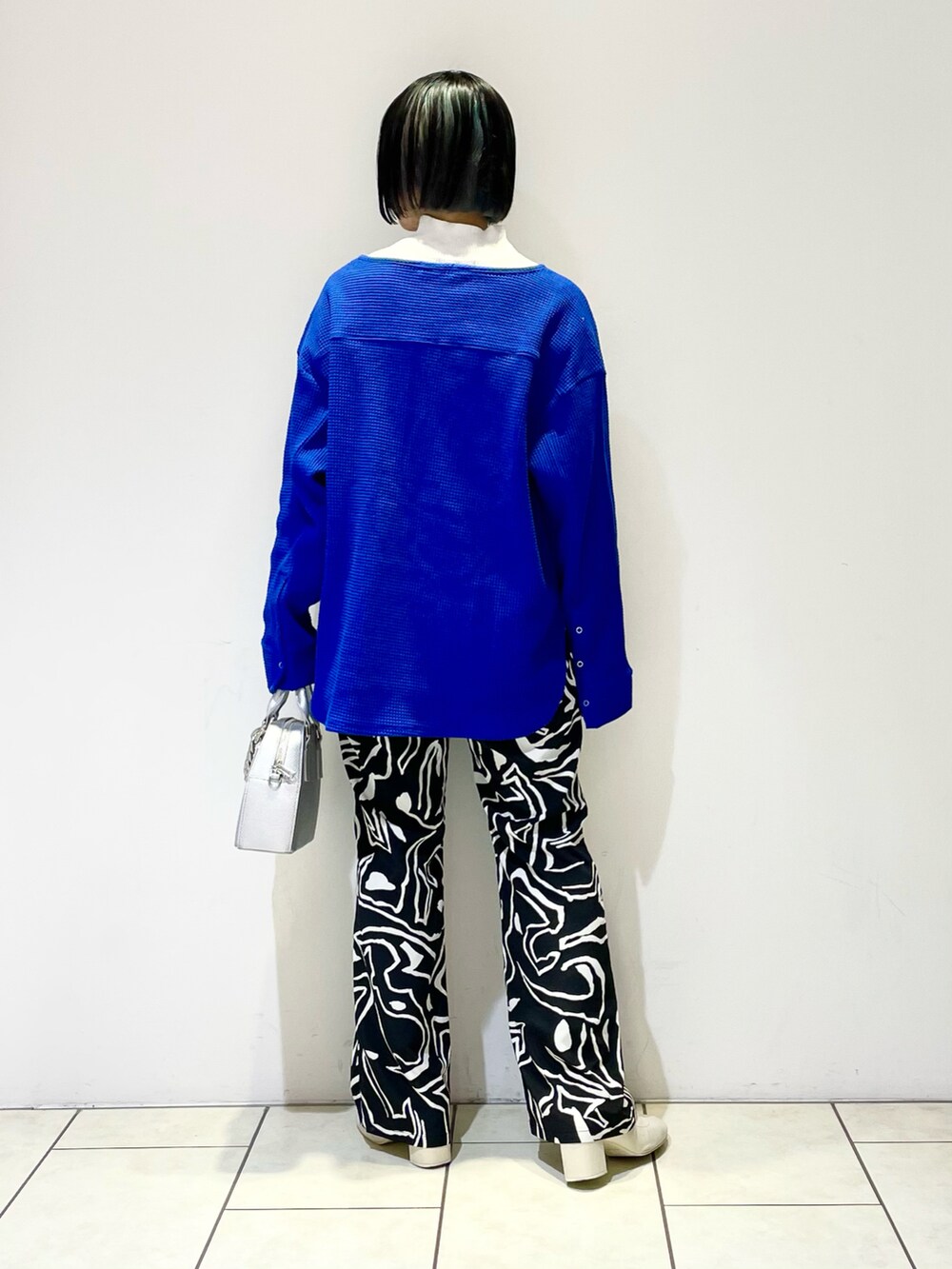 ブルー系のTシャツ/カットソー、ホワイト系のニット/セーター、シルバー系のショルダーバッグを着用したレディースの春コーディネートの3枚目の写真