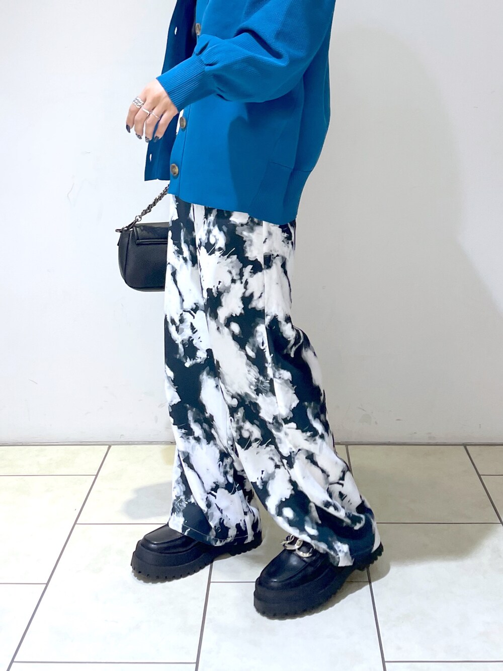 ブラック系のニット/セーター、ブルー系のカーディガン/ボレロ、ブラック系のショルダーバッグを着用したレディースの秋コーディネートの5枚目の写真