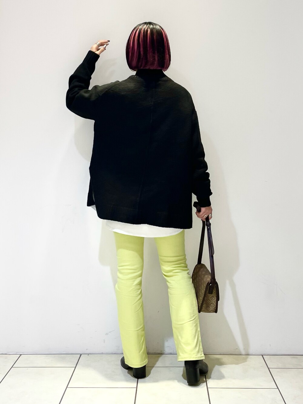 ブラック系のニット/セーター、ホワイト系のTシャツ/カットソー、ブラウン系のショルダーバッグを着用したレディースの春コーディネートの3枚目の写真