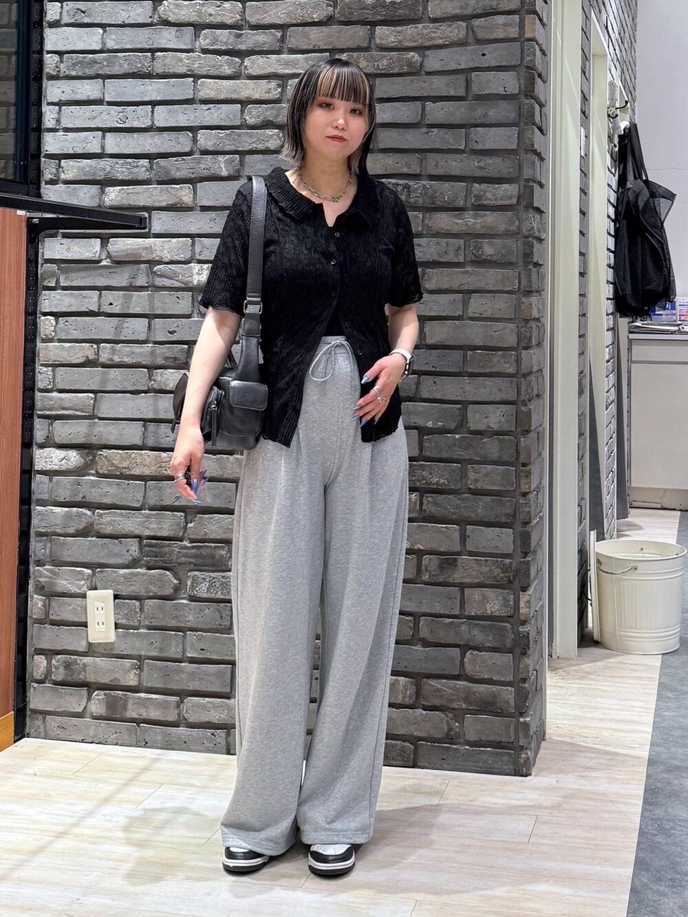 ブラック系のショルダーバッグ、ブラック系のシャツ/ブラウス、グレー系のスウェットパンツを着用したレディースの春コーディネートの3枚目の写真
