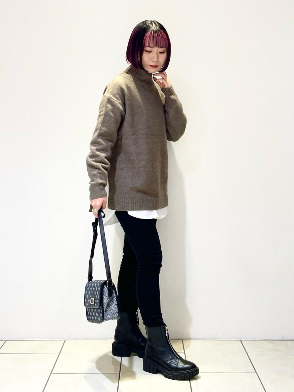 ブラウン系のニット/セーター、ホワイト系のTシャツ/カットソー、ブラック系のショルダーバッグを着用したレディースの冬コーディネートの2枚目の写真