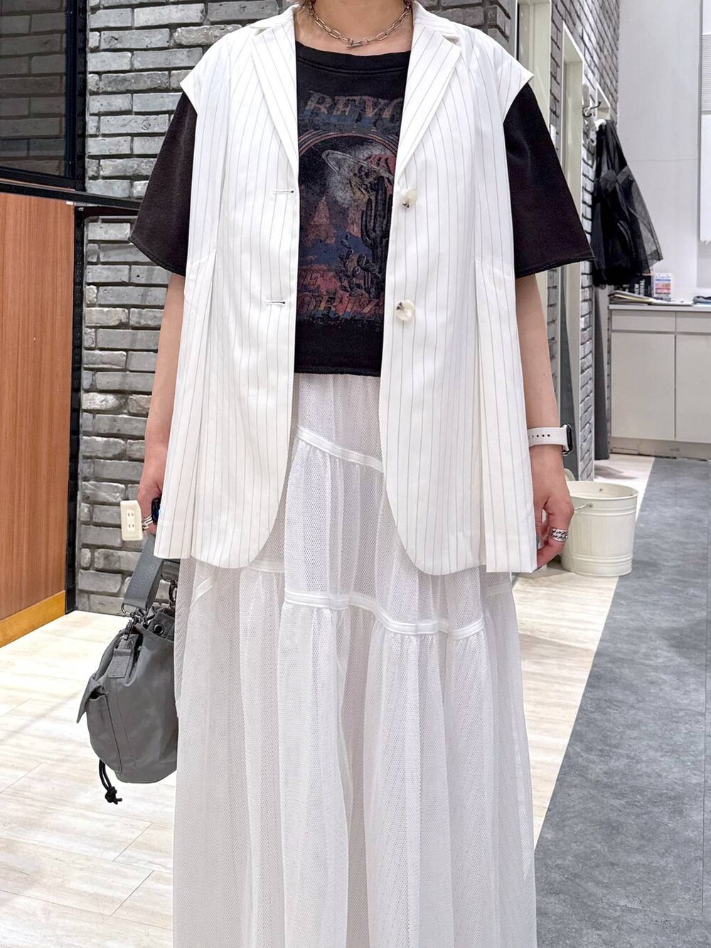 ブラック系のサンダル、ベージュ系のショルダーバッグ、ホワイト系のベストを着用したレディースの春コーディネートの3枚目の写真