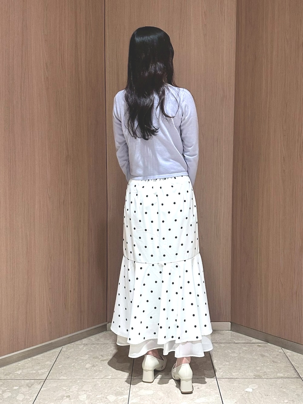 ホワイト系のショルダーバッグ、ブルー系のニット/セーター、ホワイト系のスカートを着用したレディースの冬コーディネートの2枚目の写真