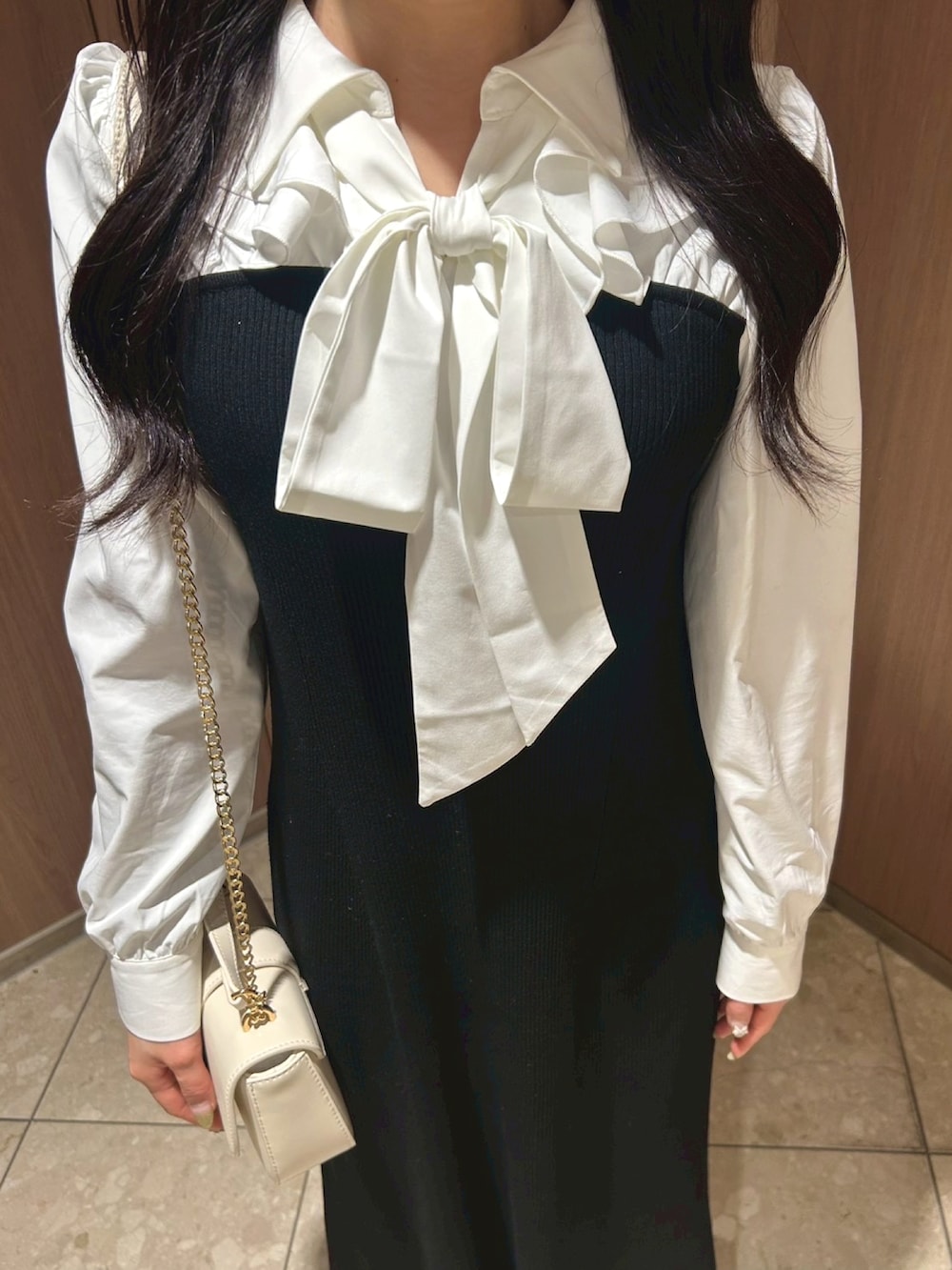 ホワイト系のショルダーバッグ、ブラック系のワンピース、ベージュ系のスニーカーを着用したレディースの冬コーディネートの3枚目の写真