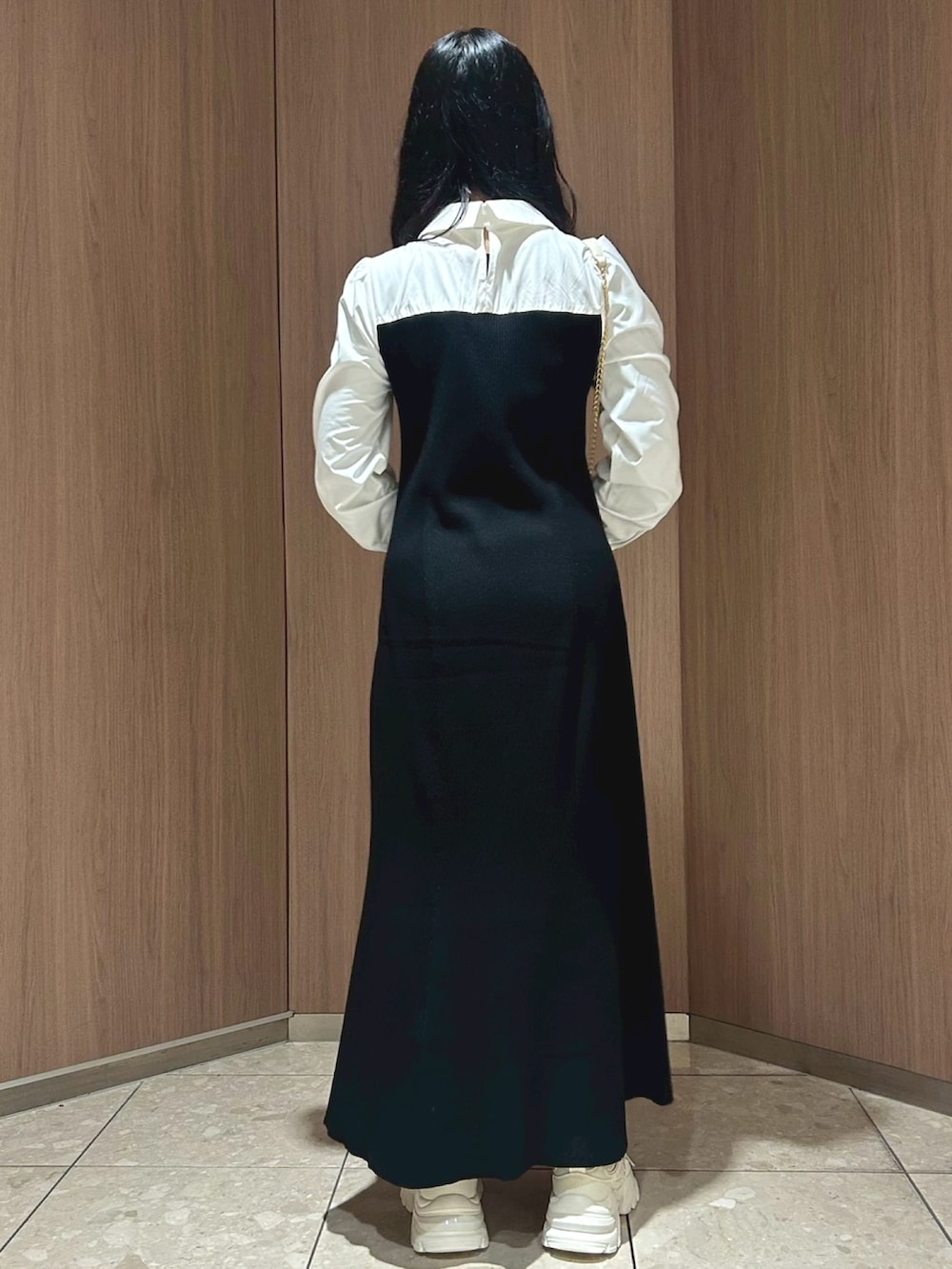 ホワイト系のショルダーバッグ、ブラック系のワンピース、ベージュ系のスニーカーを着用したレディースの冬コーディネートの2枚目の写真