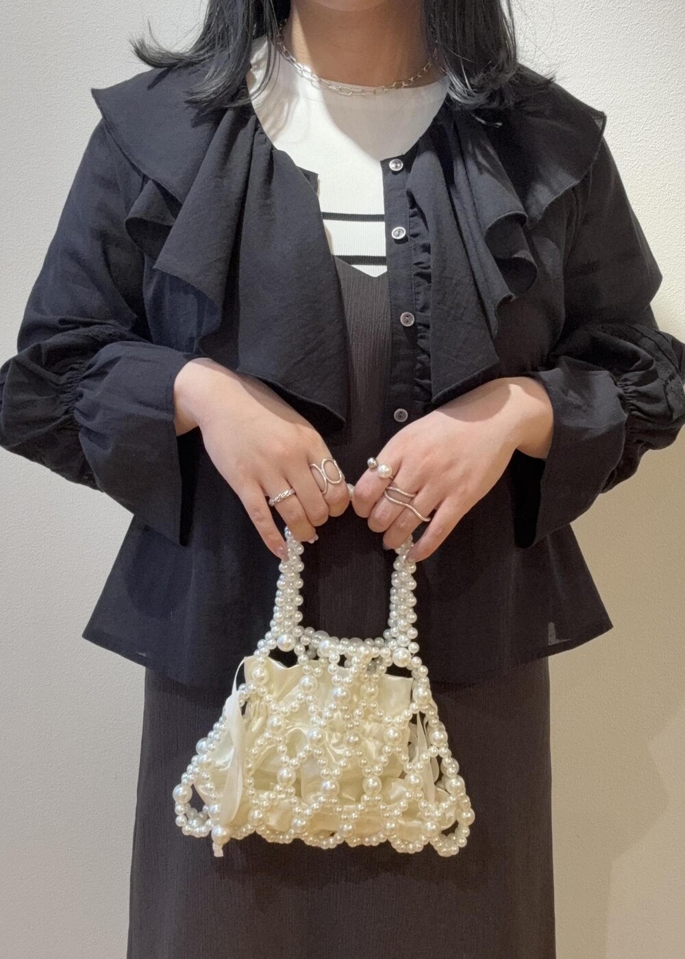 グレー系のワンピース、ブラック系のシャツ/ブラウス、ホワイト系のニット/セーターを着用したレディースの春コーディネートの4枚目の写真