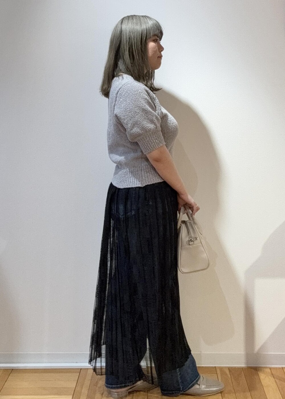 ブラック系のスカート、ベージュ系のボストンバッグ、グレー系のローファーを着用したレディースの春コーディネートの2枚目の写真