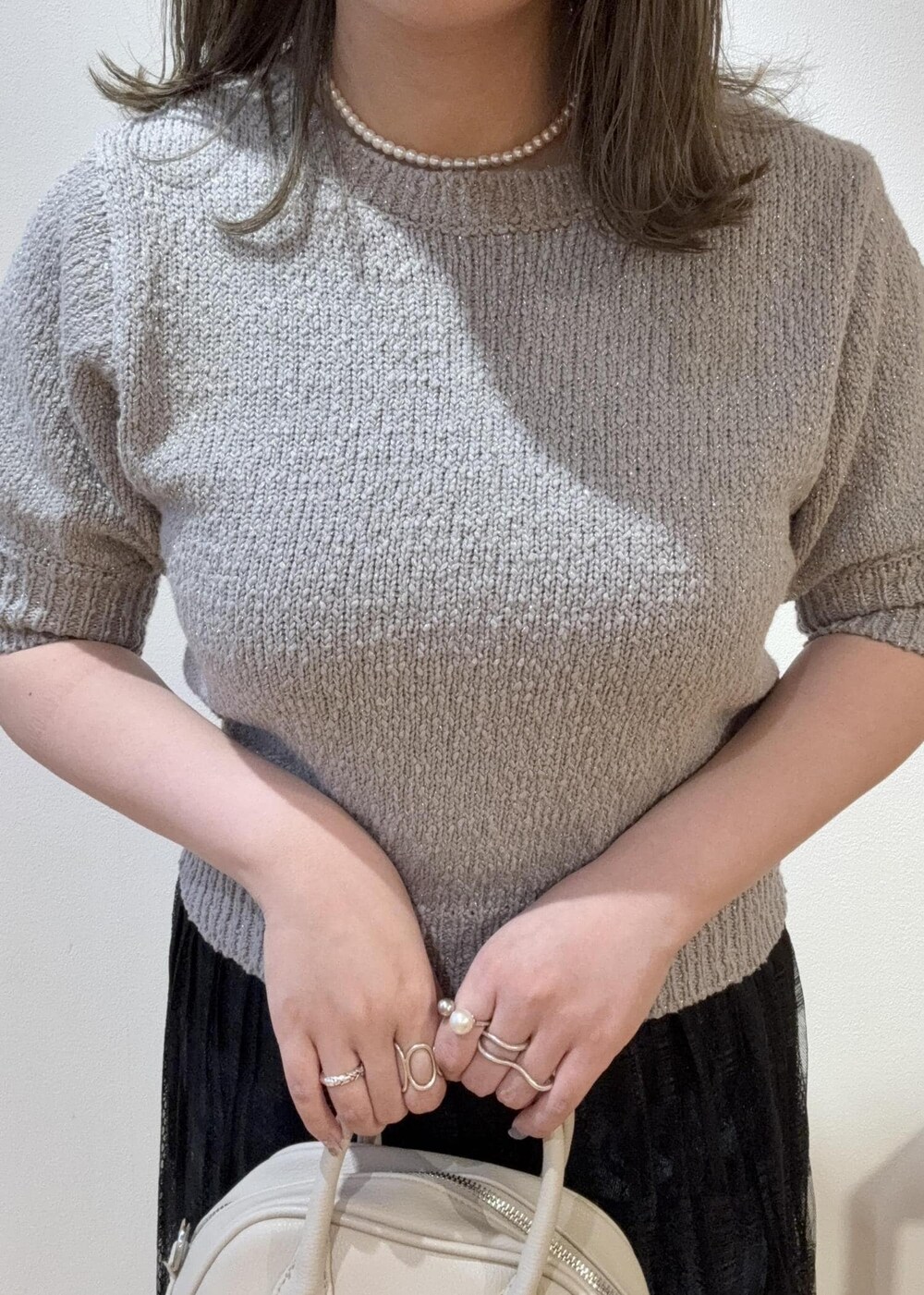 ブラック系のスカート、ベージュ系のボストンバッグ、グレー系のローファーを着用したレディースの春コーディネートの4枚目の写真