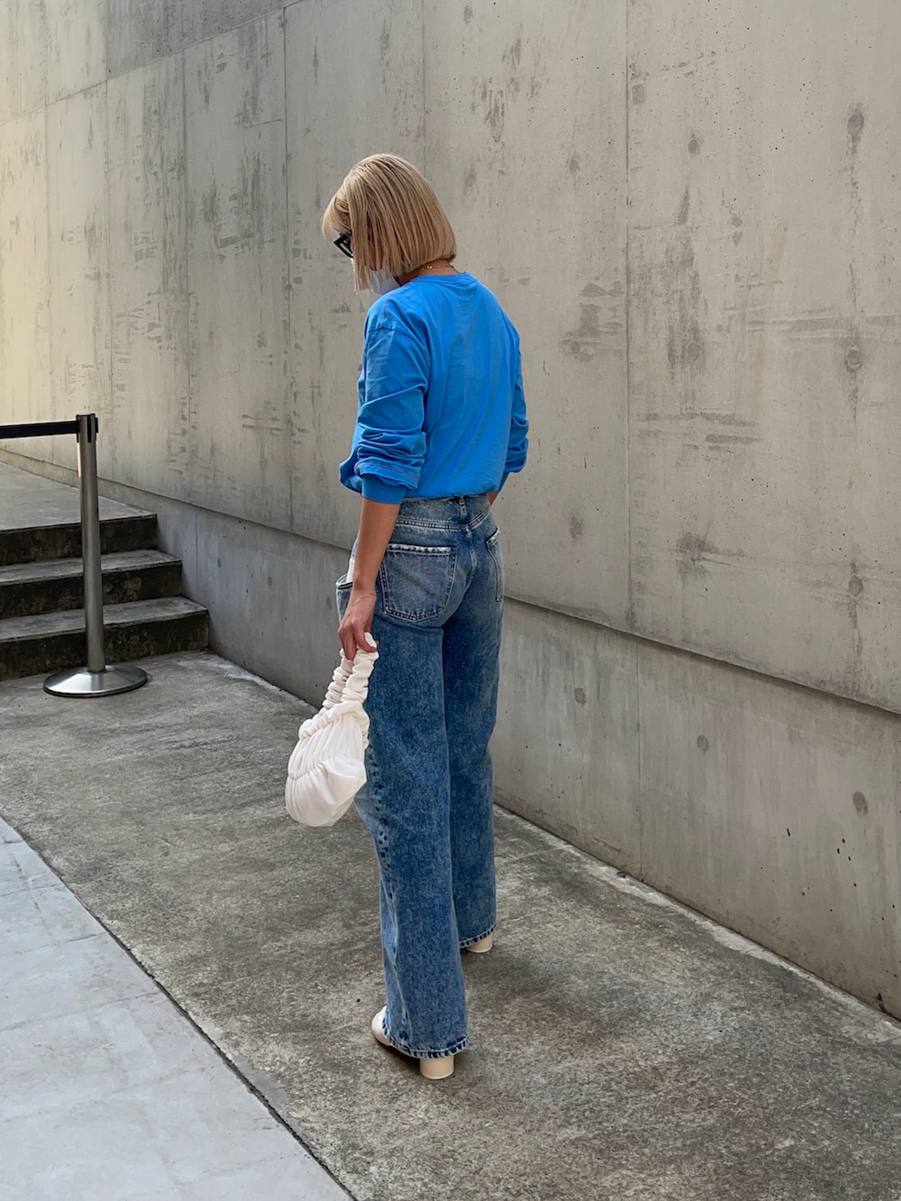 ブルー系のデニムパンツ、ホワイト系のブーツ、ブルー系のTシャツ/カットソーを着用したレディースの春コーディネートの2枚目の写真