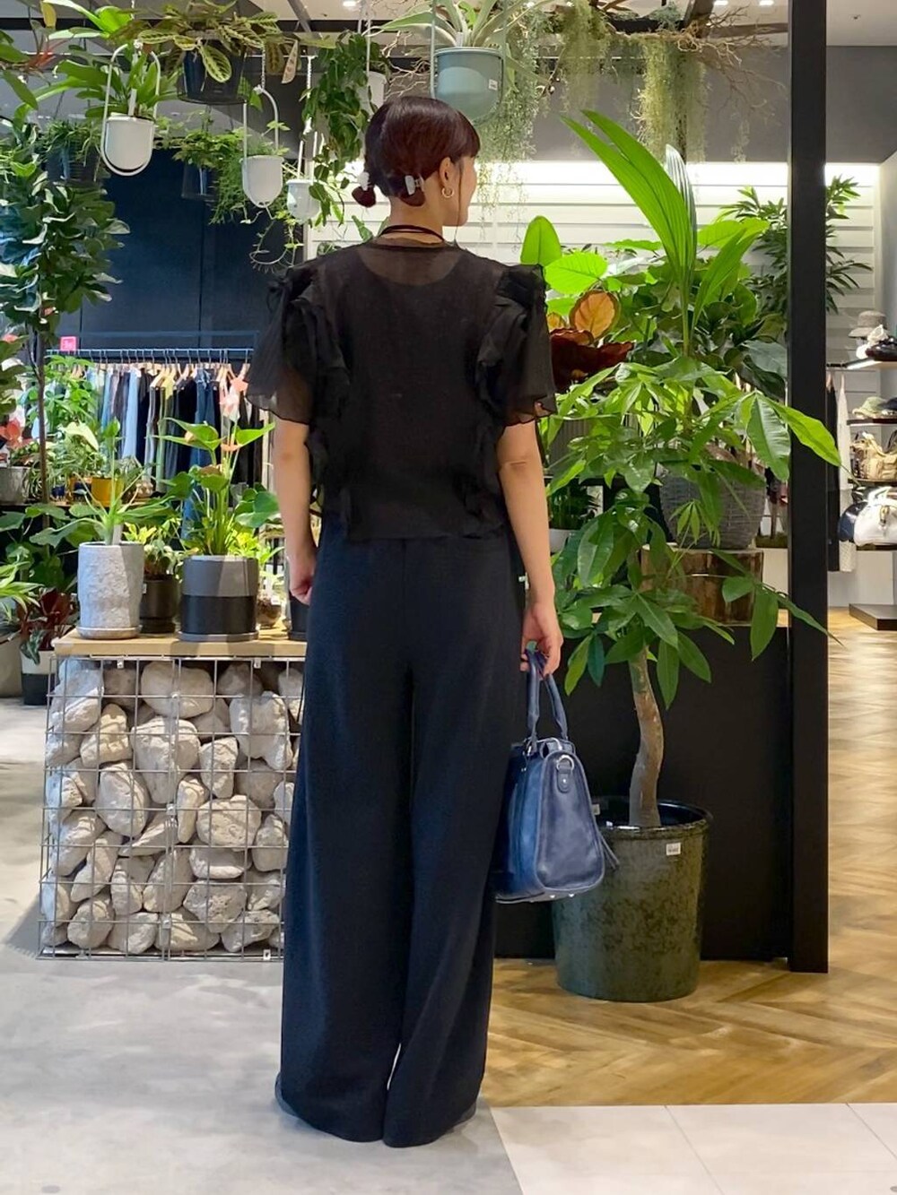 グレー系のタンクトップ、ブルー系のボストンバッグ、ブラック系のスウェットパンツを着用したレディースの夏コーディネートの4枚目の写真