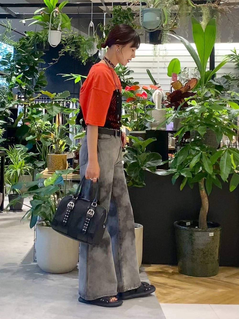 ブラック系のサンダル、ブラック系のボストンバッグ、グレー系のデニムパンツを着用したレディースの夏コーディネートの2枚目の写真