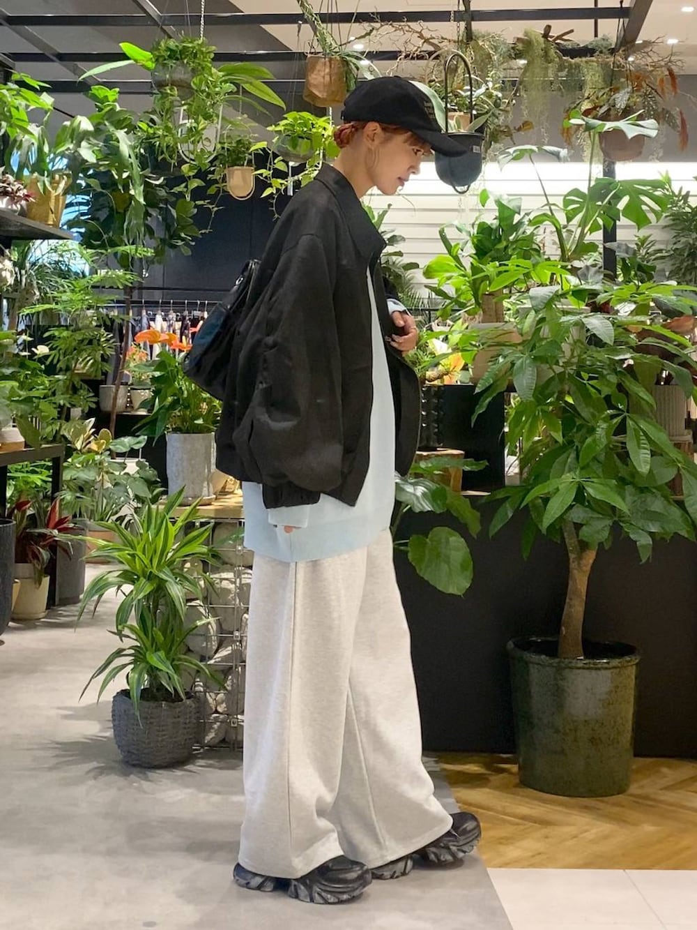 ブルー系のニット/セーター、ブラック系のブルゾン、ブラック系のスニーカーを着用したレディースの秋コーディネートの2枚目の写真