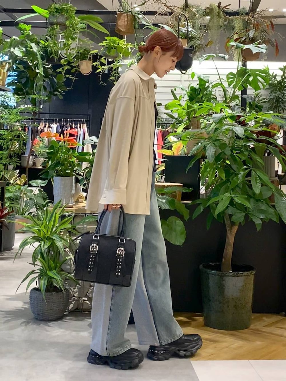 ブラック系のローファー、ブルー系のデニムパンツ、ブラック系のボストンバッグを着用したレディースの秋コーディネートの2枚目の写真