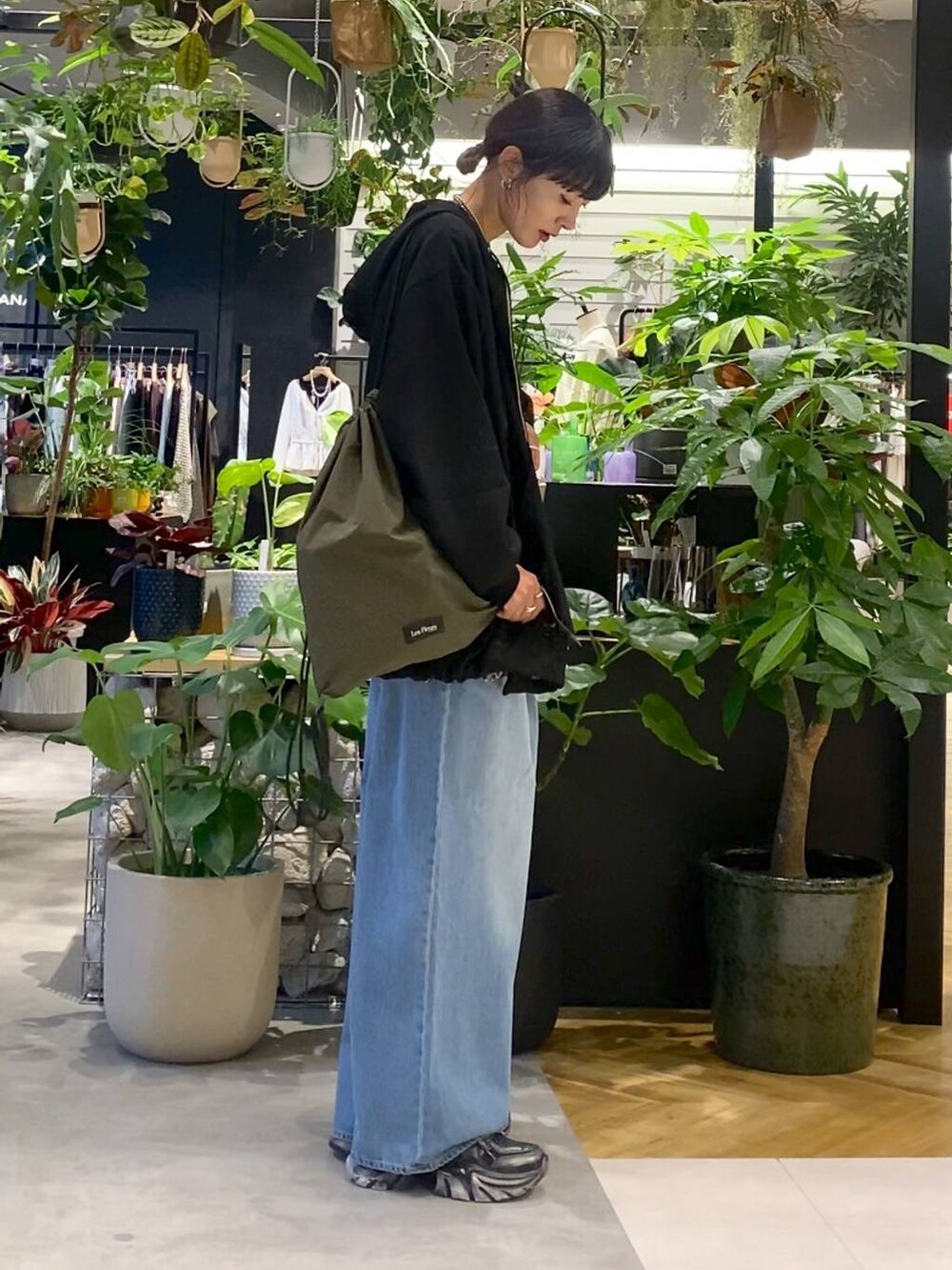 ブルー系のデニムパンツ、ブラック系のパーカー、ブラック系のスニーカーを着用したレディースの秋コーディネートの3枚目の写真