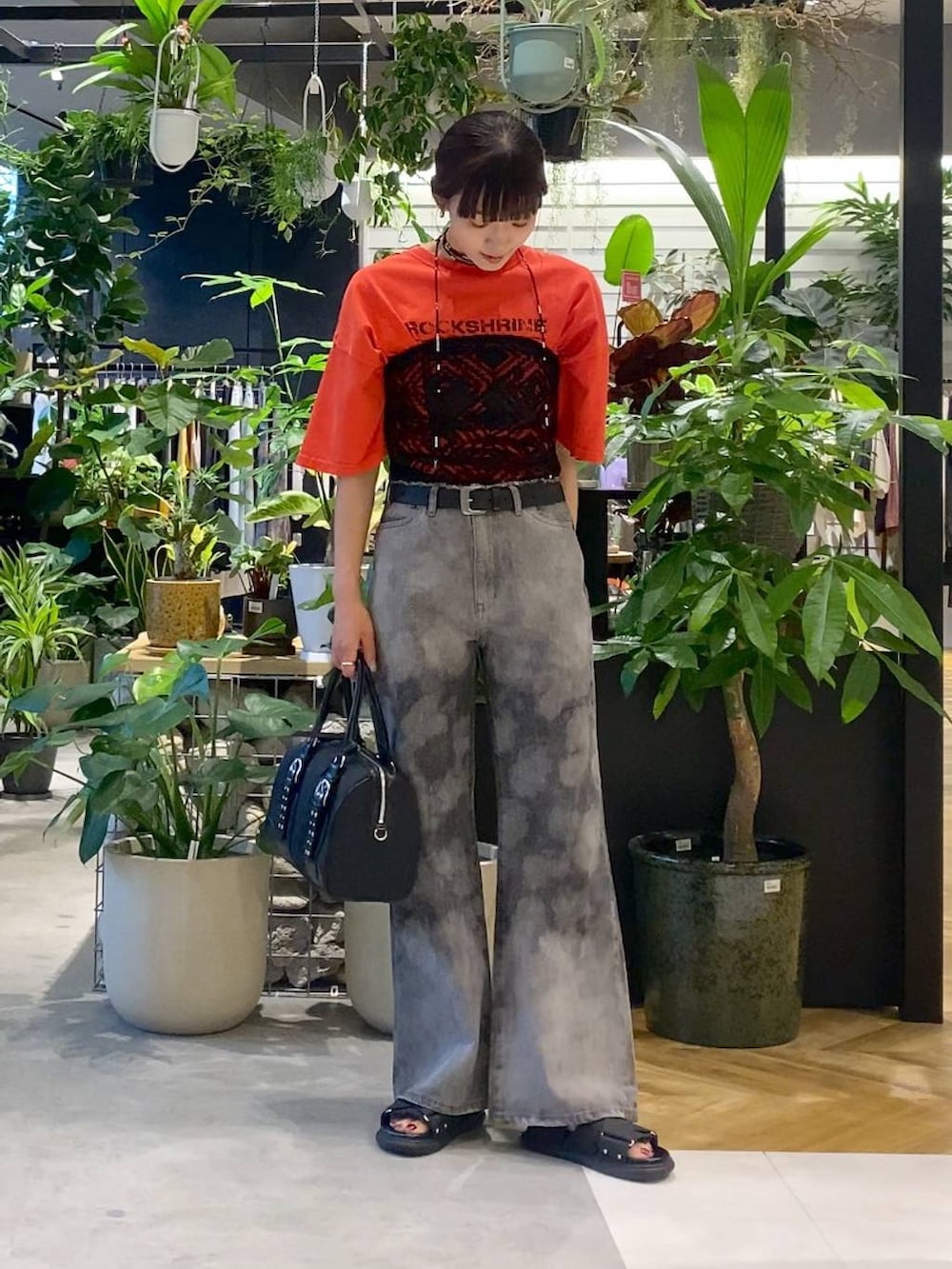 ブラック系のサンダル、ブラック系のボストンバッグ、グレー系のデニムパンツを着用したレディースの夏コーディネートの3枚目の写真