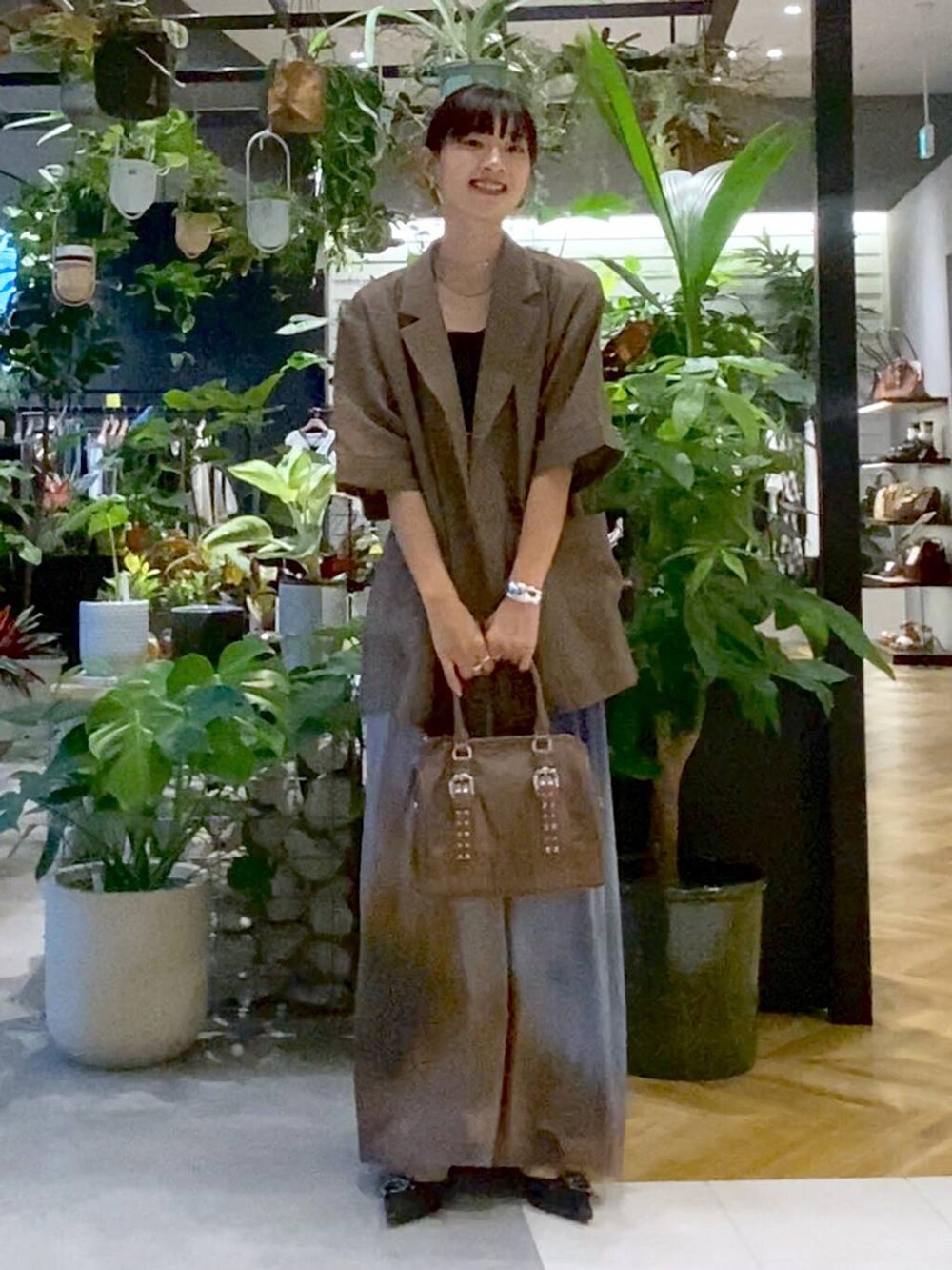 ブラック系のパンプス、グリーン系のボストンバッグ、ブルー系のスカートを着用したレディースの夏コーディネートの3枚目の写真