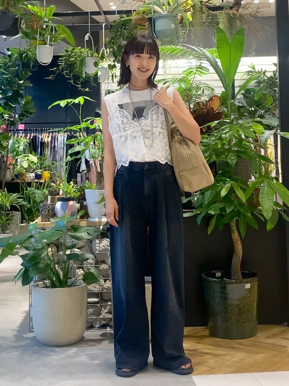 ベージュ系のショルダーバッグ、ブラック系のデニムパンツ、ブラック系のサンダルを着用したレディースの夏コーディネートの2枚目の写真