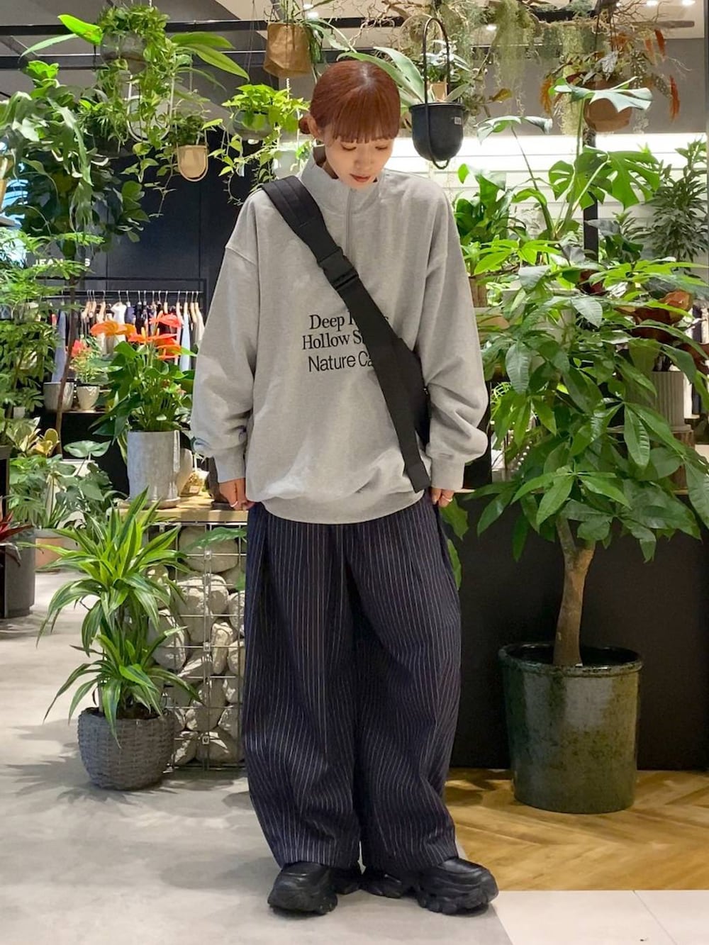 ブラック系のショルダーバッグ、ブラック系のローファー、ブルー系のスラックスを着用したレディースの秋コーディネートの5枚目の写真