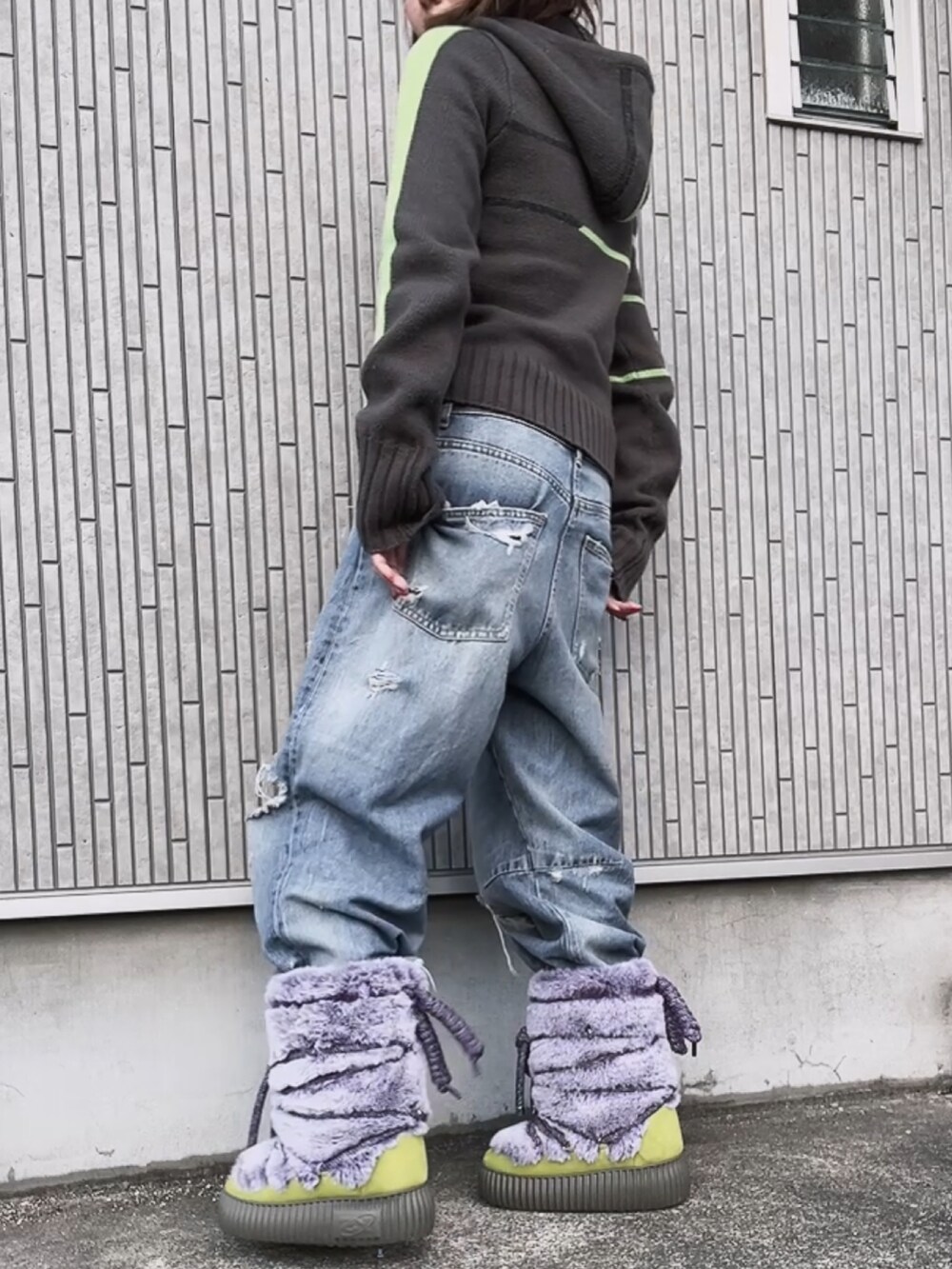 グレー系のニット/セーター、パープル系のブーツ、ブルー系のデニムパンツを着用したレディースの冬コーディネートの2枚目の写真