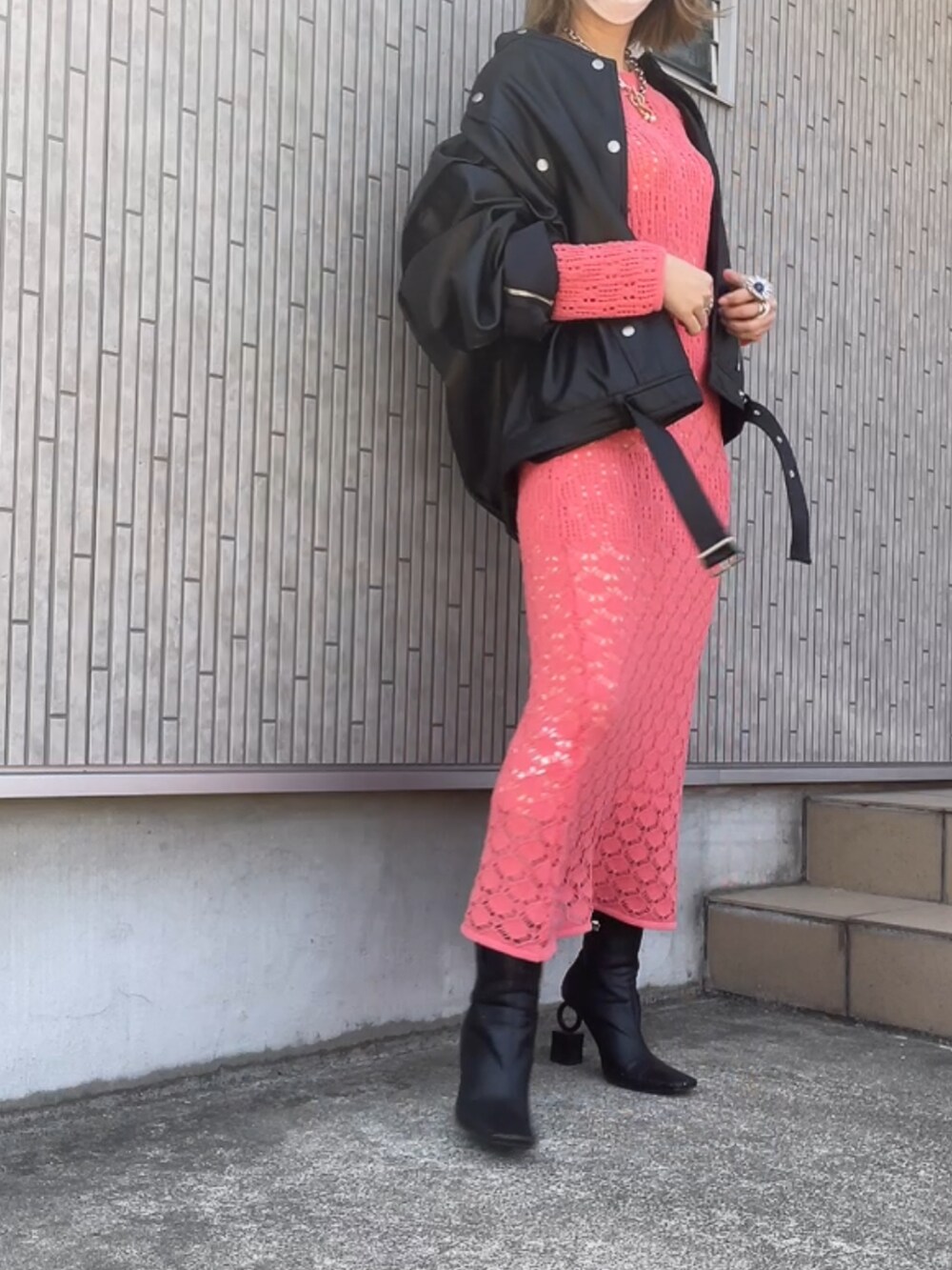 ブラック系のライダースジャケット、ピンク系のワンピース、ブラック系のブーツを着用したレディースの春コーディネートの2枚目の写真