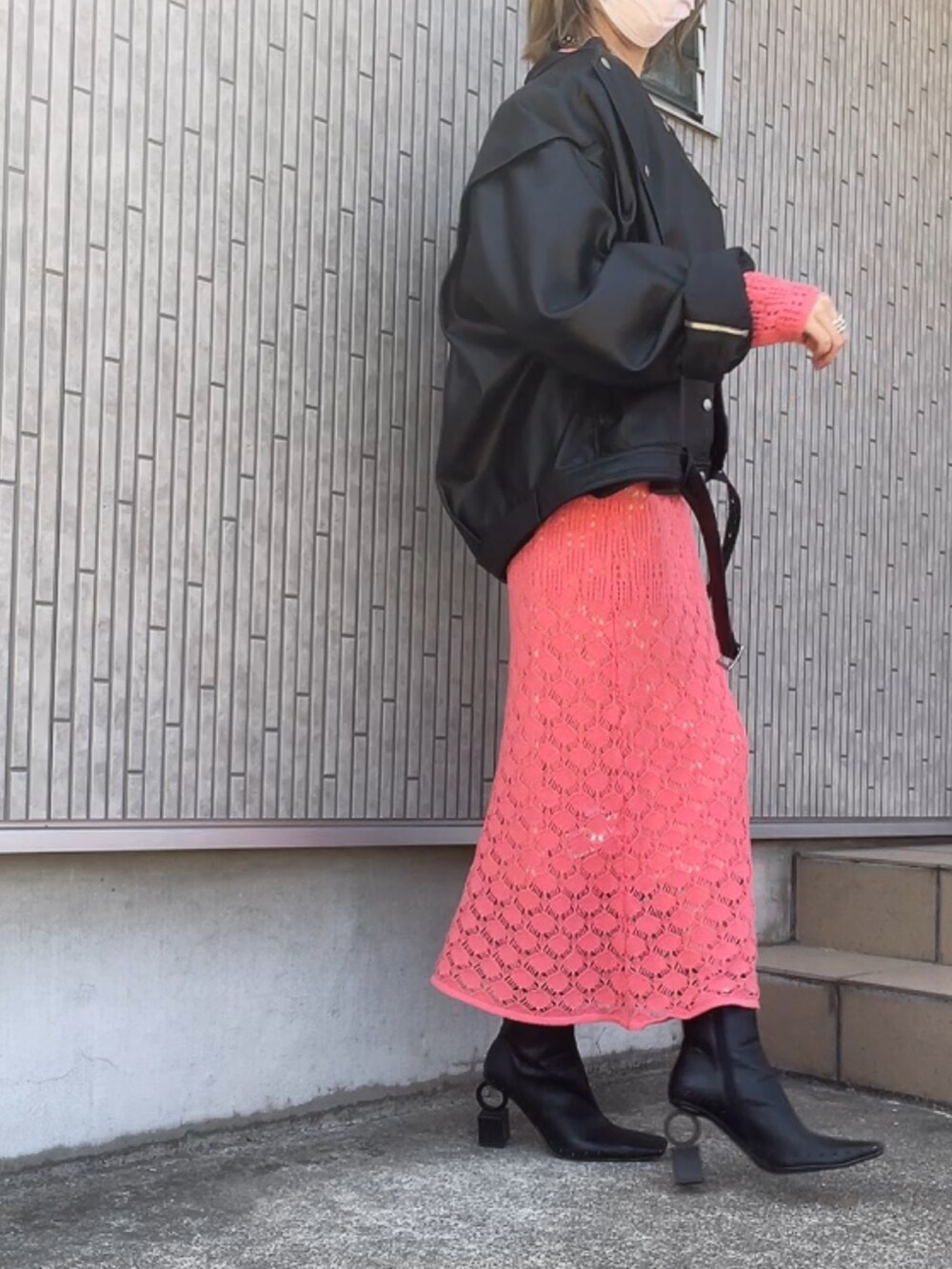 ブラック系のライダースジャケット、ピンク系のワンピース、ブラック系のブーツを着用したレディースの春コーディネートの3枚目の写真