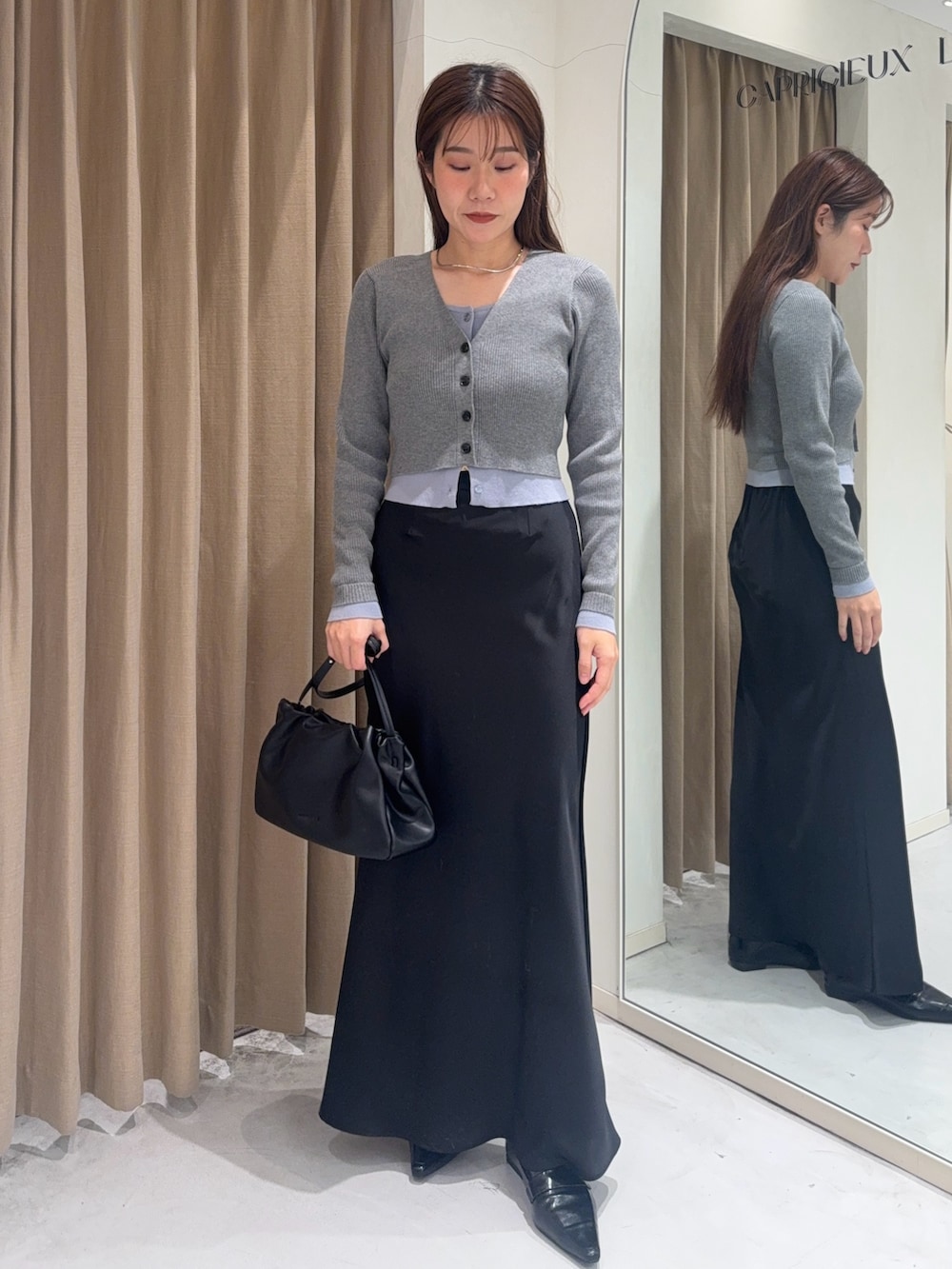 グレー系のカーディガン/ボレロ、ブラック系のスカート、ブラック系のショルダーバッグを着用したレディースの冬コーディネートの2枚目の写真