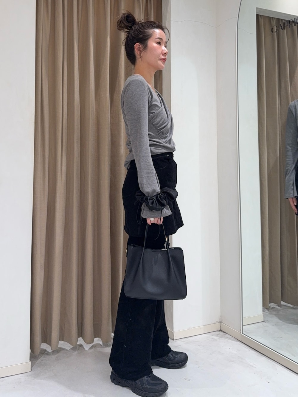 グレー系のTシャツ/カットソー、ブラック系のスカート、ブラック系のトートバッグを着用したレディースの冬コーディネートの5枚目の写真