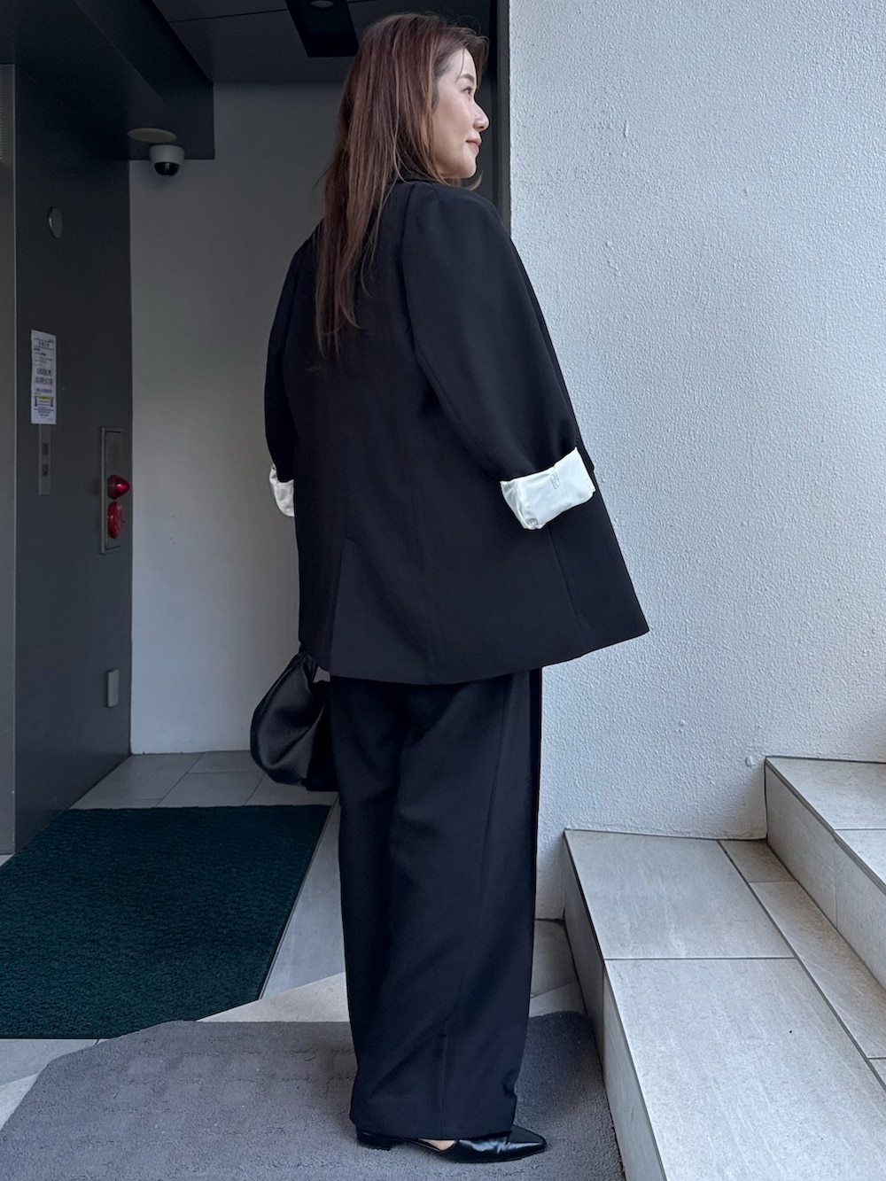 ブラック系のテーラードジャケット、グレー系のカーディガン/ボレロ、ブラック系のショルダーバッグを着用したレディースの冬コーディネートの3枚目の写真