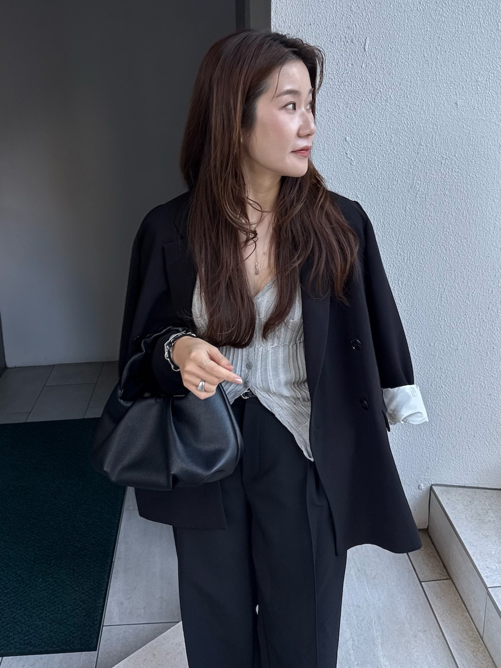 ブラック系のテーラードジャケット、グレー系のカーディガン/ボレロ、ブラック系のショルダーバッグを着用したレディースの冬コーディネートの4枚目の写真