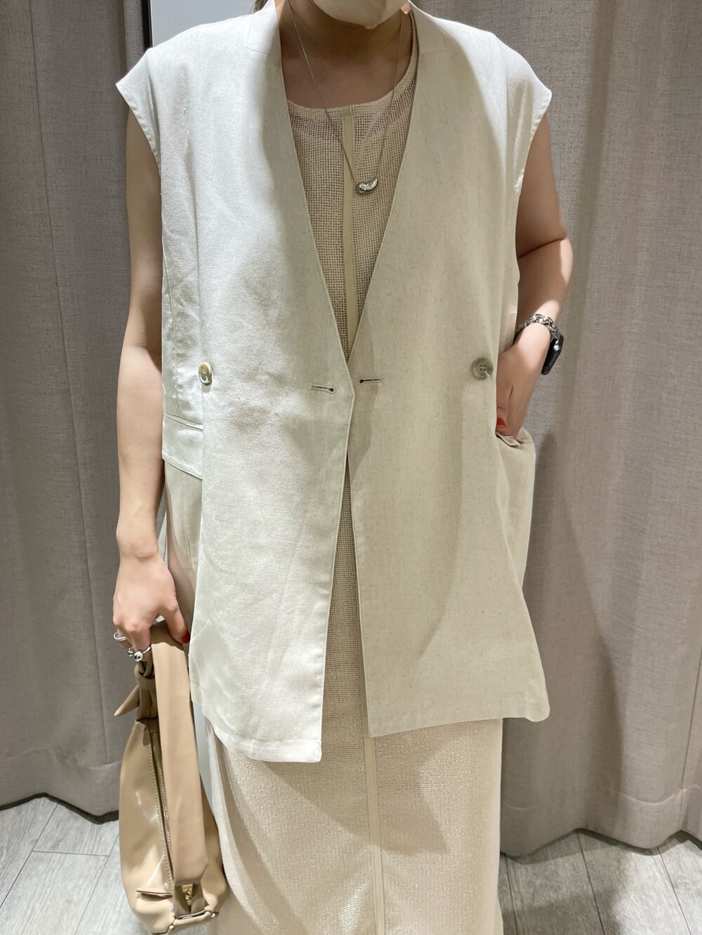 ホワイト系のベスト、ホワイト系のワンピース、ベージュ系のショルダーバッグを着用したレディースの夏コーディネートの3枚目の写真