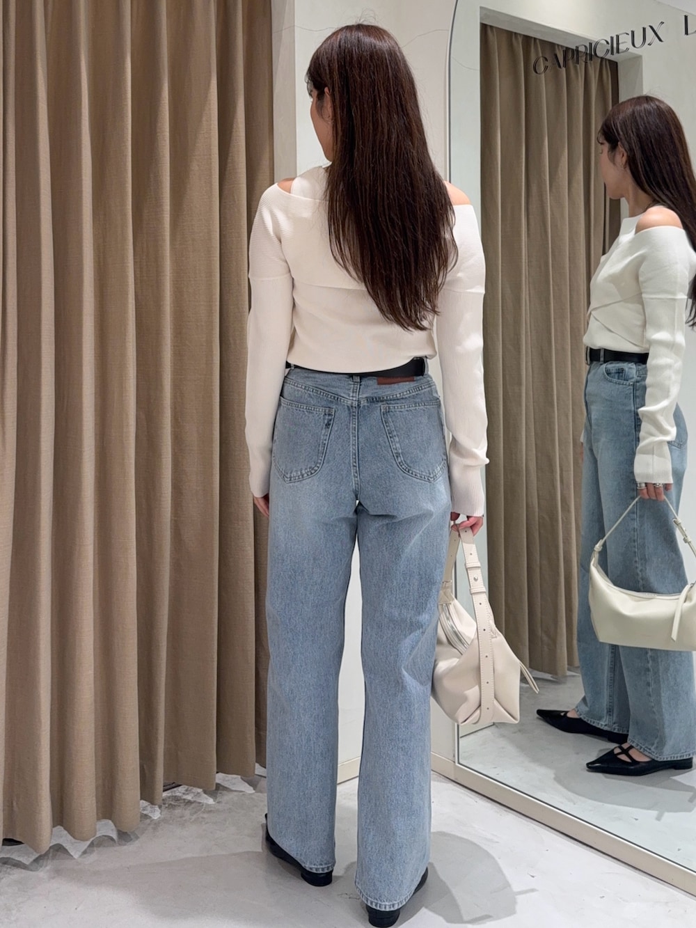 ホワイト系のニット/セーター、ブラック系のパンプス、ホワイト系のショルダーバッグを着用したレディースの冬コーディネートの3枚目の写真