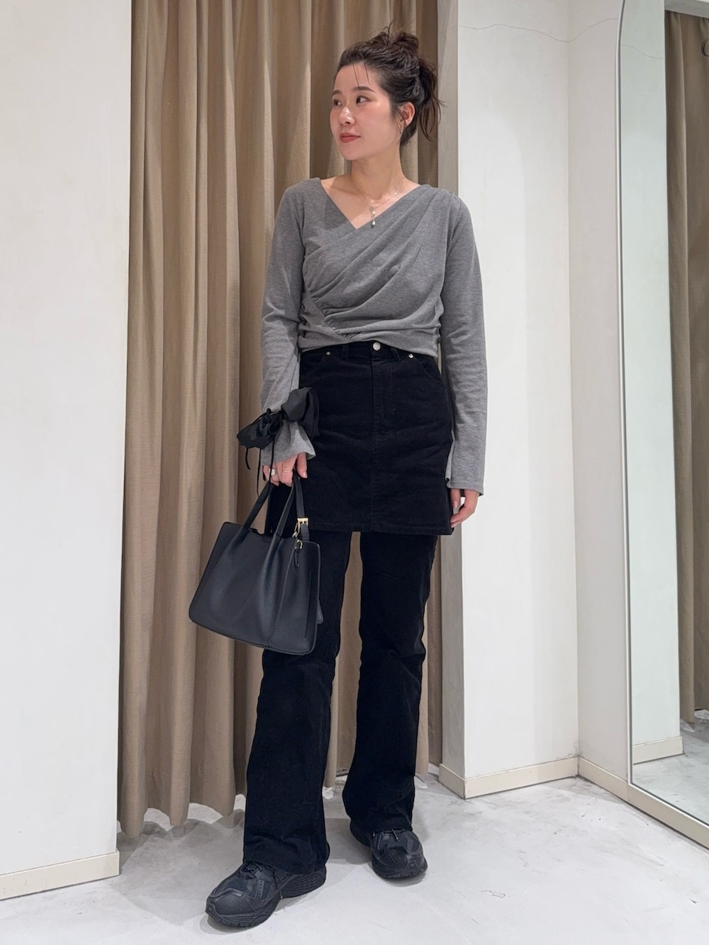 グレー系のTシャツ/カットソー、ブラック系のスカート、ブラック系のトートバッグを着用したレディースの冬コーディネートの2枚目の写真