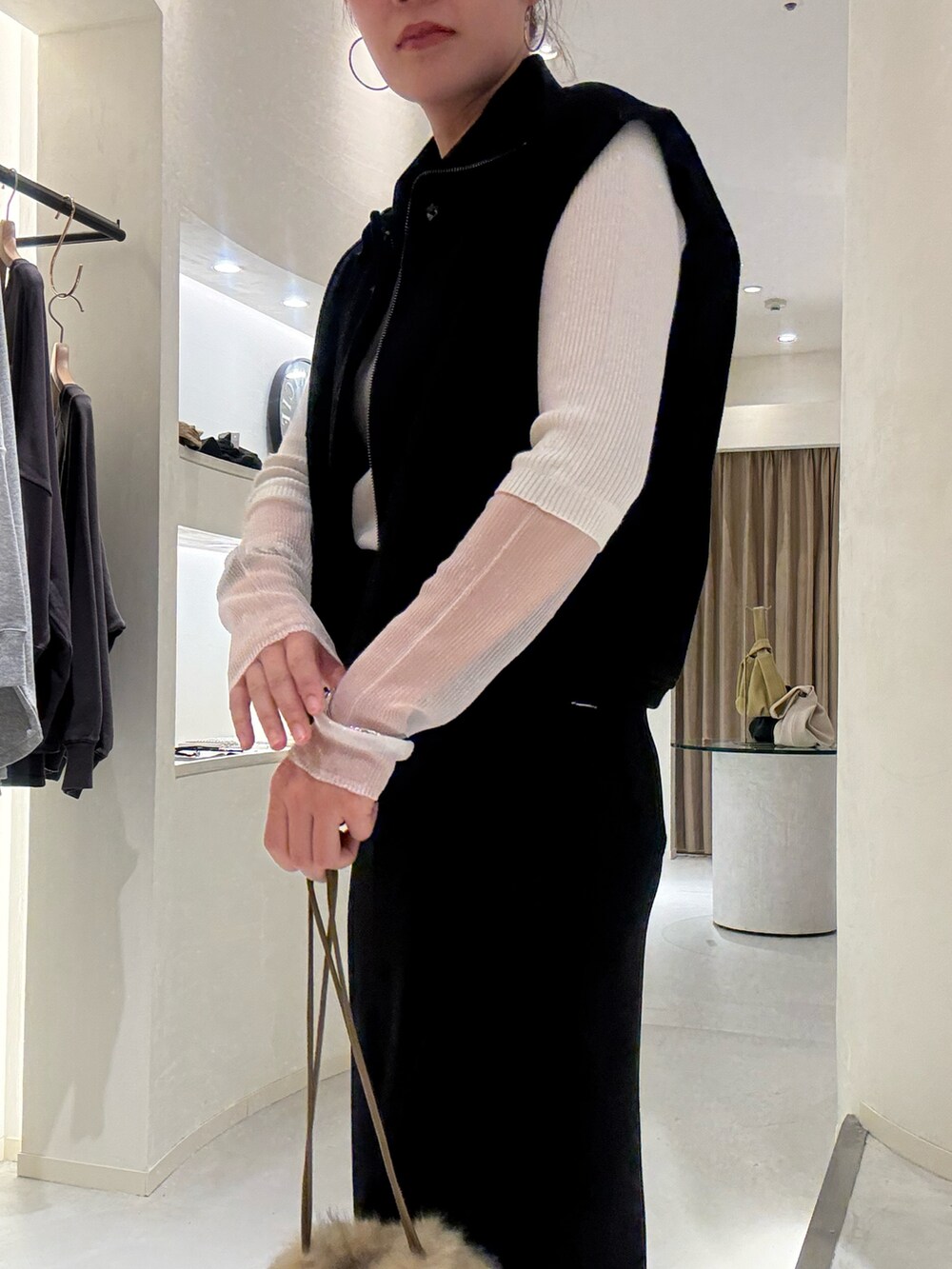 ブラック系のベスト、ホワイト系のTシャツ/カットソー、ブラック系のスカートを着用したレディースの冬コーディネートの3枚目の写真