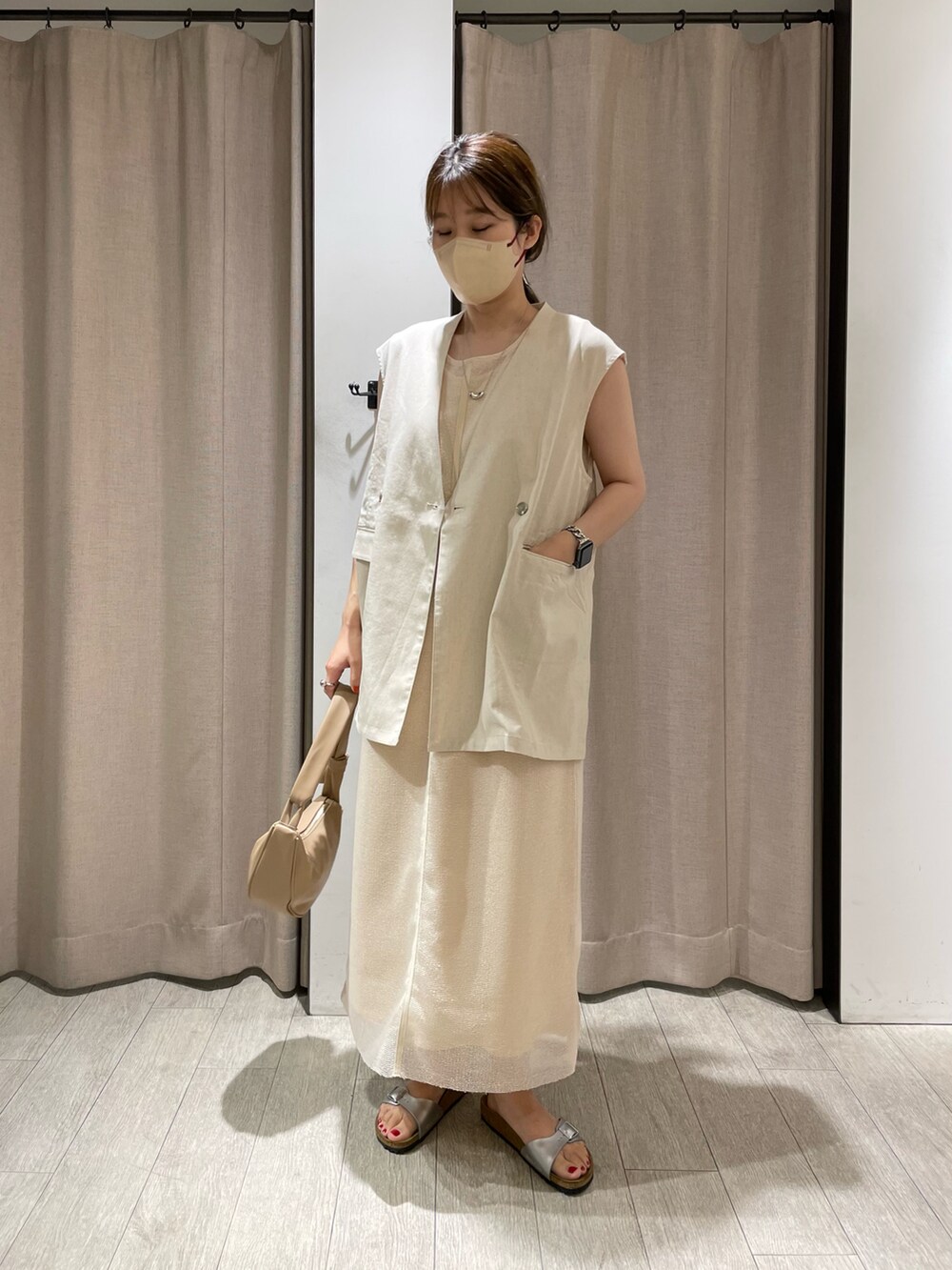 ホワイト系のベスト、ホワイト系のワンピース、ベージュ系のショルダーバッグを着用したレディースの夏コーディネートの2枚目の写真