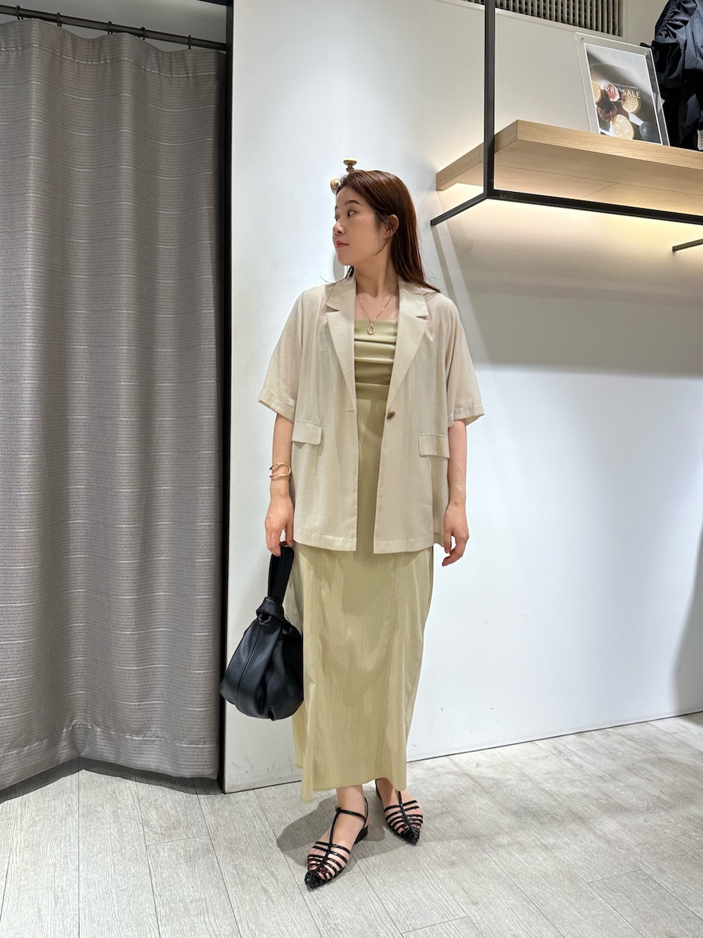 ホワイト系のテーラードジャケット、ベージュ系のワンピース、ブラック系のハンドバッグを着用したレディースの夏コーディネートの2枚目の写真