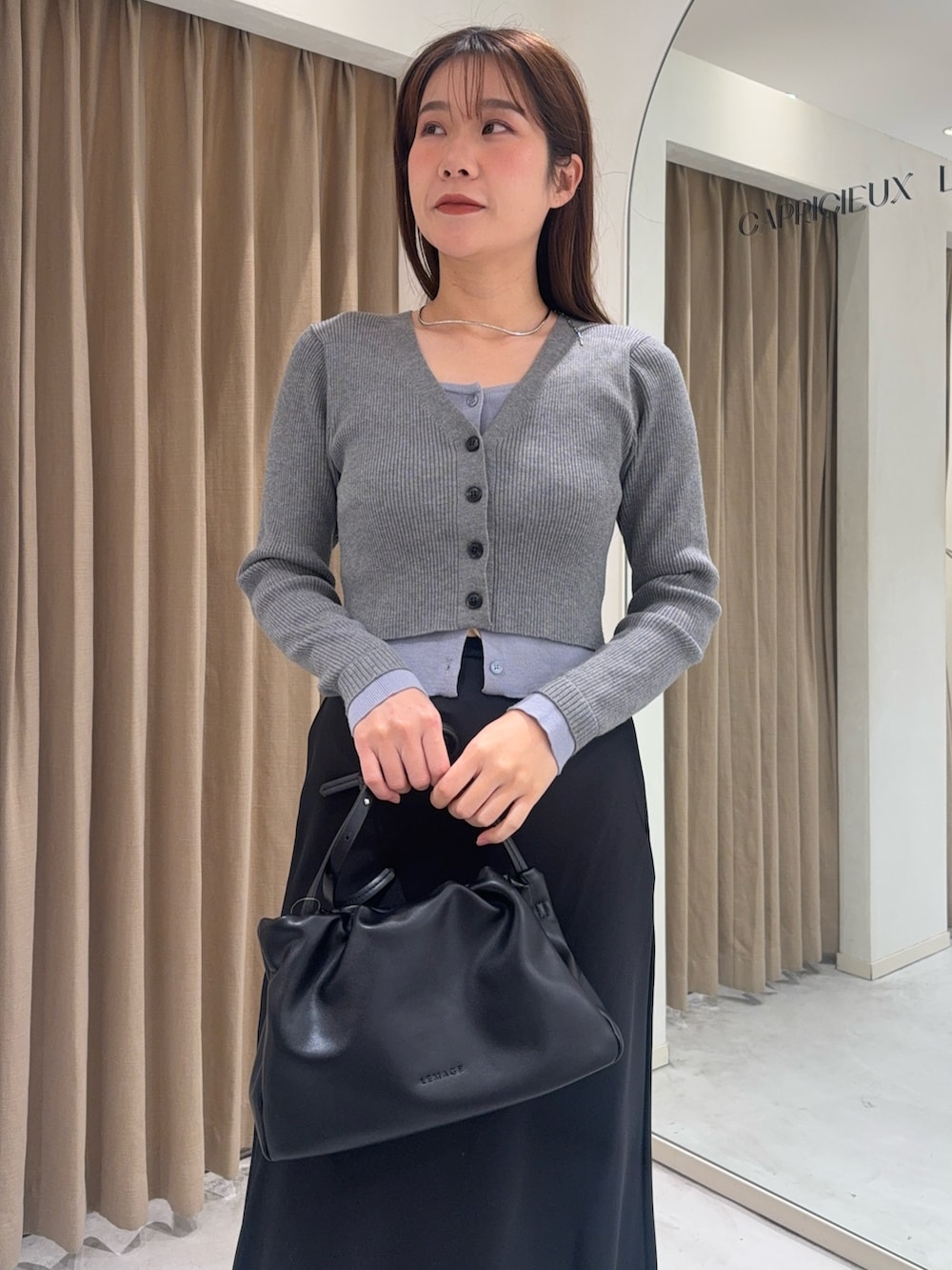 グレー系のカーディガン/ボレロ、ブラック系のスカート、ブラック系のショルダーバッグを着用したレディースの冬コーディネートの4枚目の写真